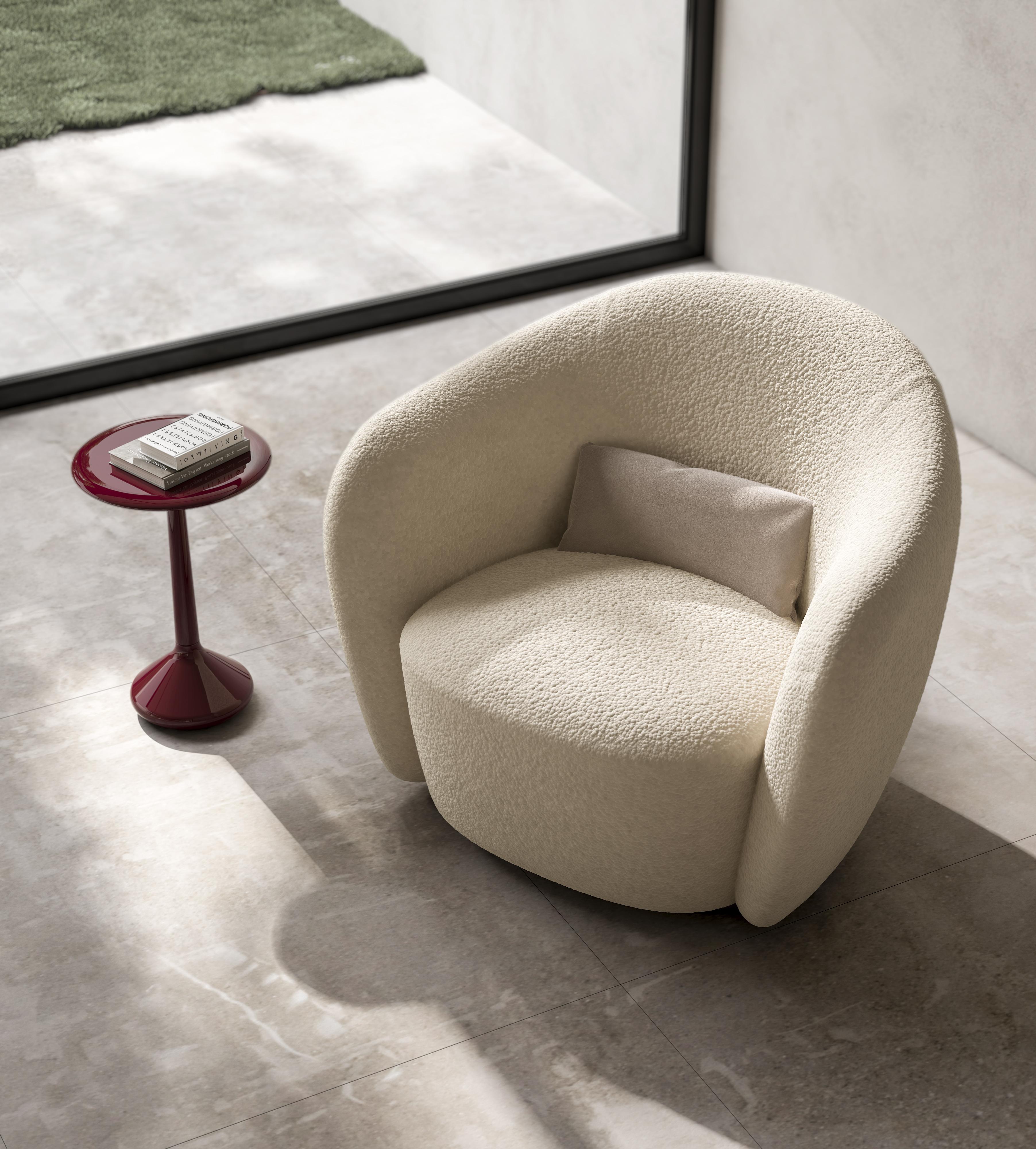 Este sillón redondo combina elegancia y comodidad con una elegante base metálica y un asiento y respaldo totalmente tapizados, disponibles en piel o tela. Su silueta curvada ofrece una sensación acogedora y acogedora, mientras que el cojín de tela