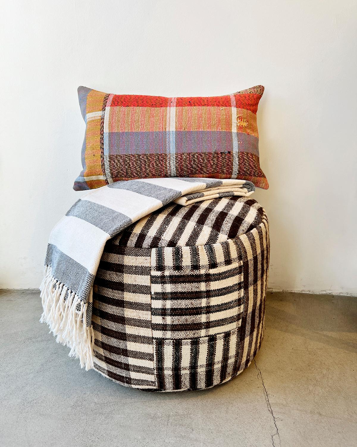 A handsome ottoman to put your feet up

A hundred years ago these fabrics used to be cereal sacks in Northern Portugal. Now they get rediscovered and transformed into a rare collectible. This wool Isabel Checkered Round Pouf Ottoman is a unique and