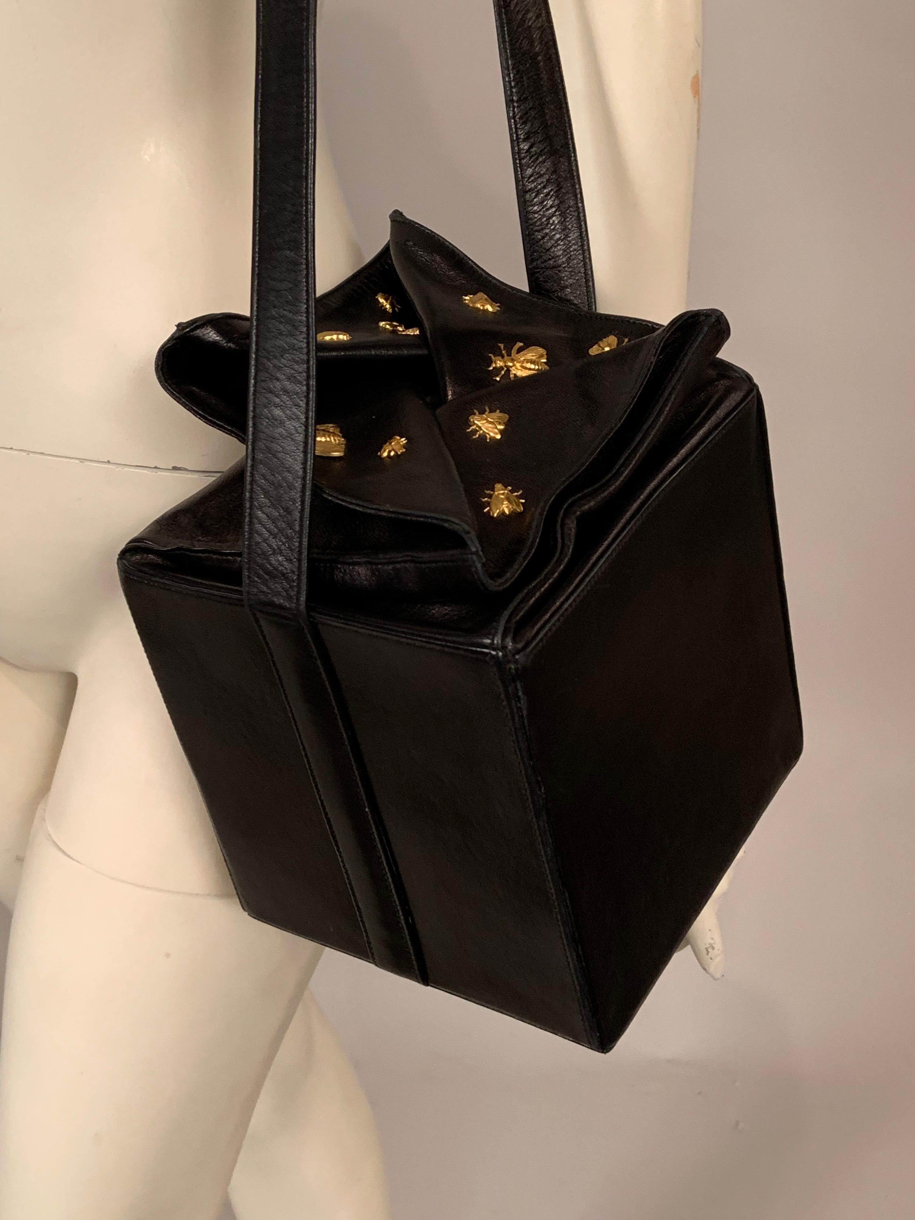 A charming and witty black lambskin leather bag, designed by Isabel Canovas has a golden bee covered folding leather top. If the bag is very full it will rise up like the top pf a beehive. The bag has long black shoulder or cross body strap, a