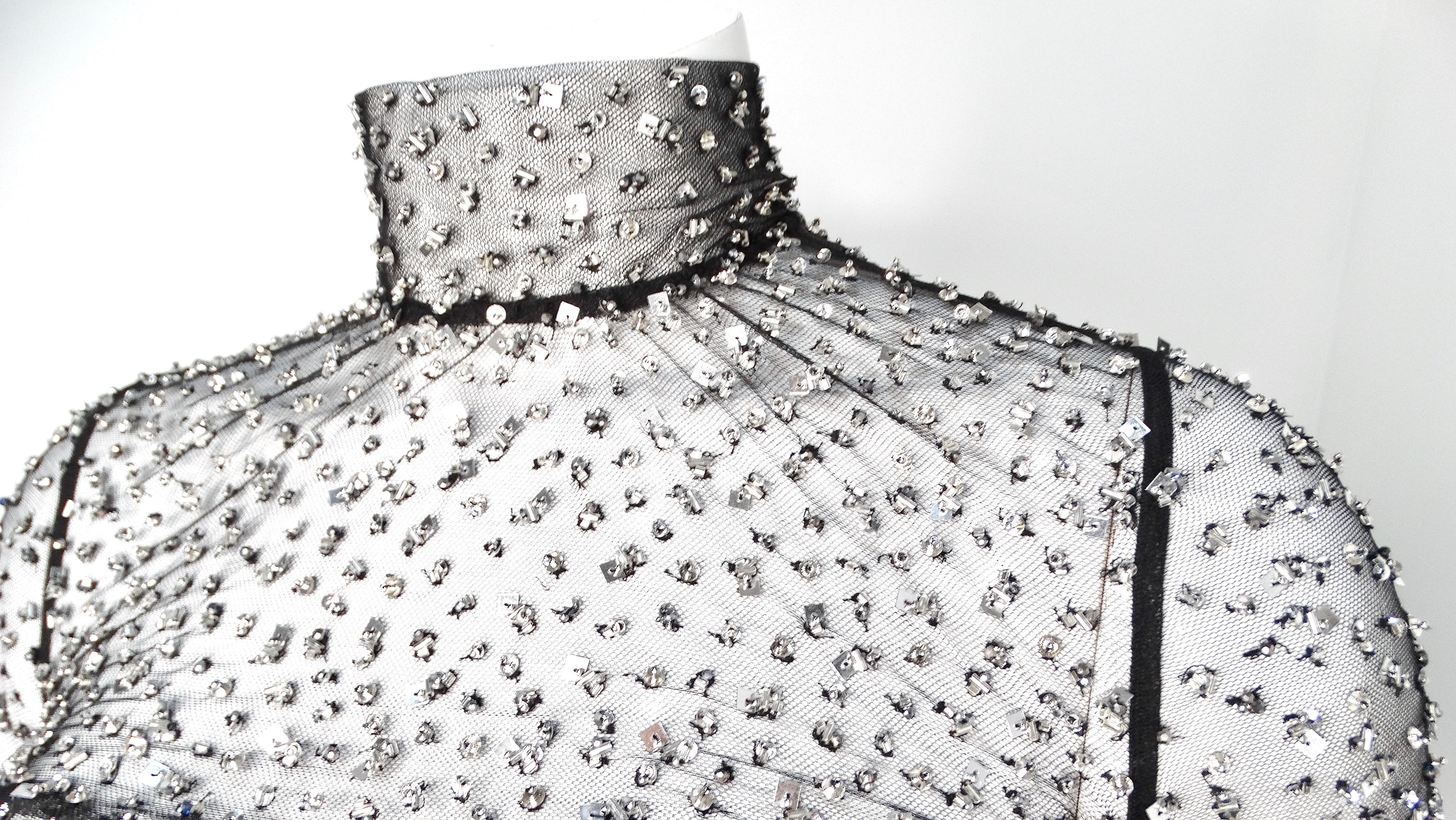 Eleva il tuo ensemble da sera con il top a maniche lunghe Todiz di Isabel Marant, un mix sorprendente di raffinatezza e glamour. Questo pezzo squisito è caratterizzato da un tessuto nero trasparente ornato da scintillanti paillettes argentate che