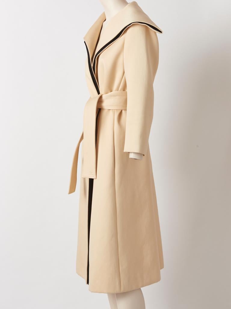 Isabel Toledo, ecru tone, heavy cotton sateen, belted coat  having no closures, a generous, standing collar doubled with black satin at the edges, also extending down the front length of the coat.