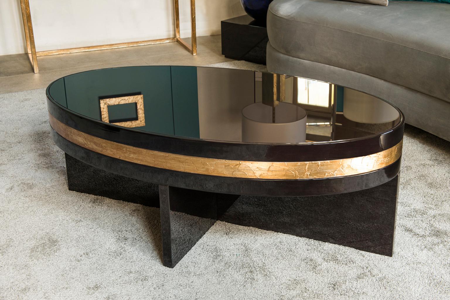 Conçue par IC et habilement fabriquée par des artisans italiens experts, la table basse Tullia présente un plateau ovale en verre posé sur une base en bois croisé. Il est enrichi d'une précieuse et élégante décoration de feuilles de bronze et