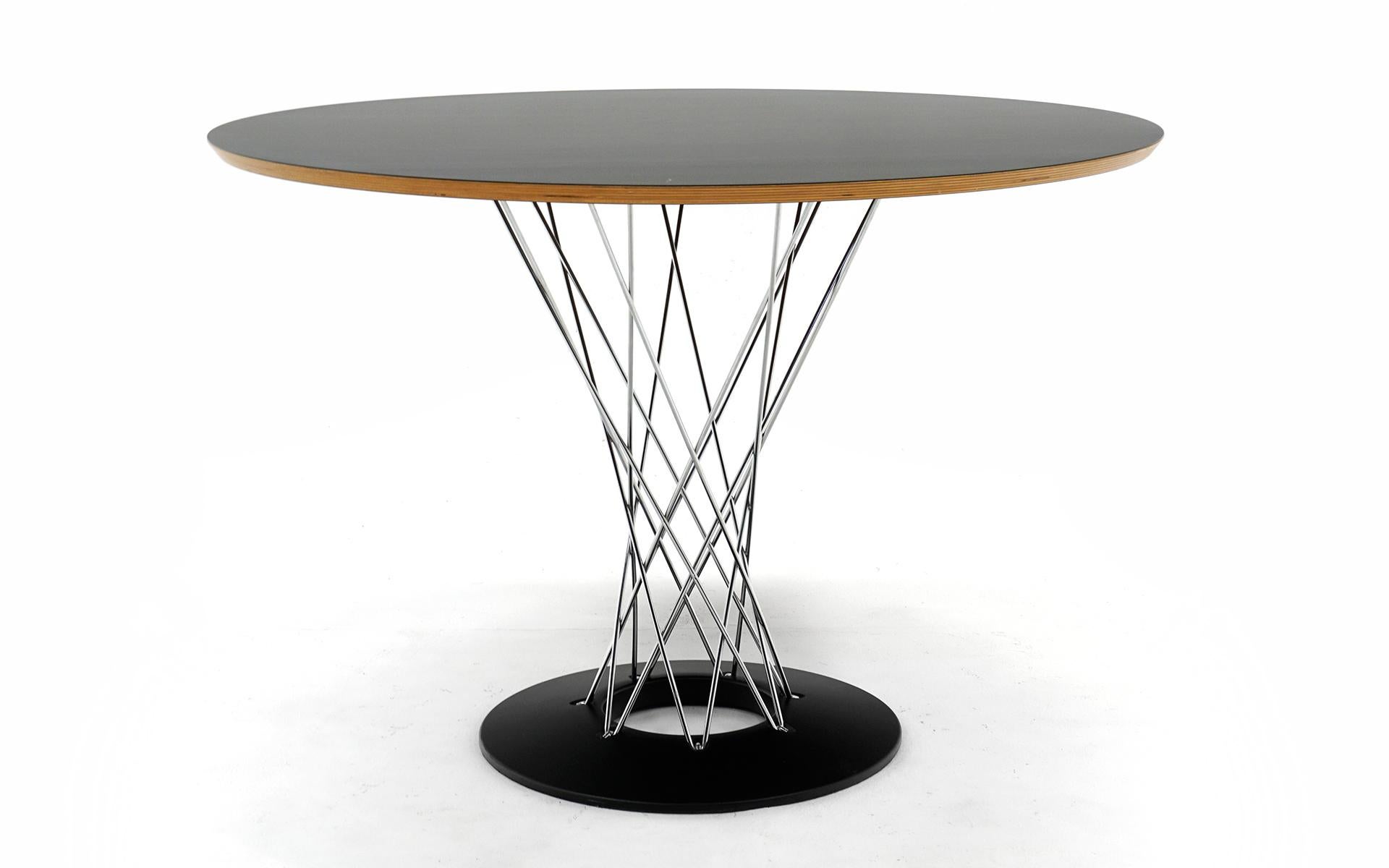 Forty two inch diameter Isamu Noguchi Cyclone dining table with black laminate top. Recent production and signed with the Knoll Studio medallion. Very good condition with no scratches to the table top. One very small nick on an edge. The chromed