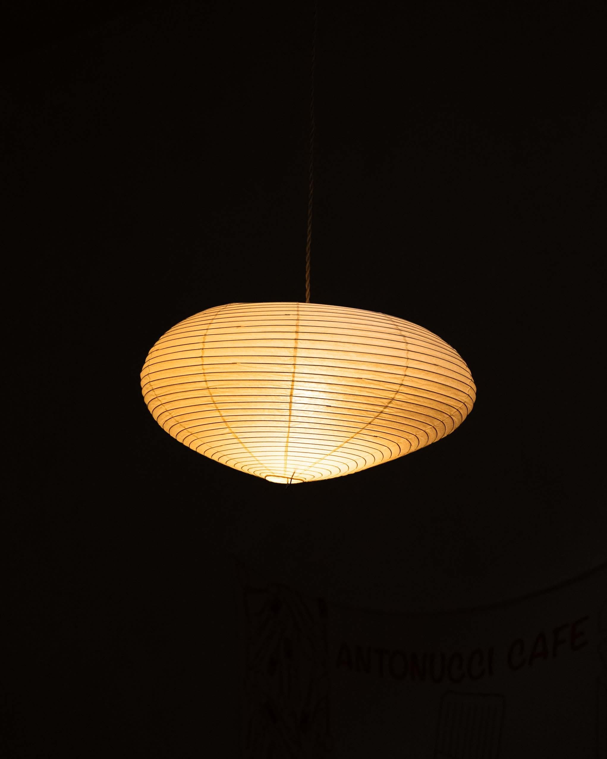 Original Akari 16A light sculpture, designed by Isamu Noguchi. The iconic lamp features a creased ovoid paper shade supported by a minimalist metal frame, exemplifying Noguchi’s blend of Japanese craft and modernist form.