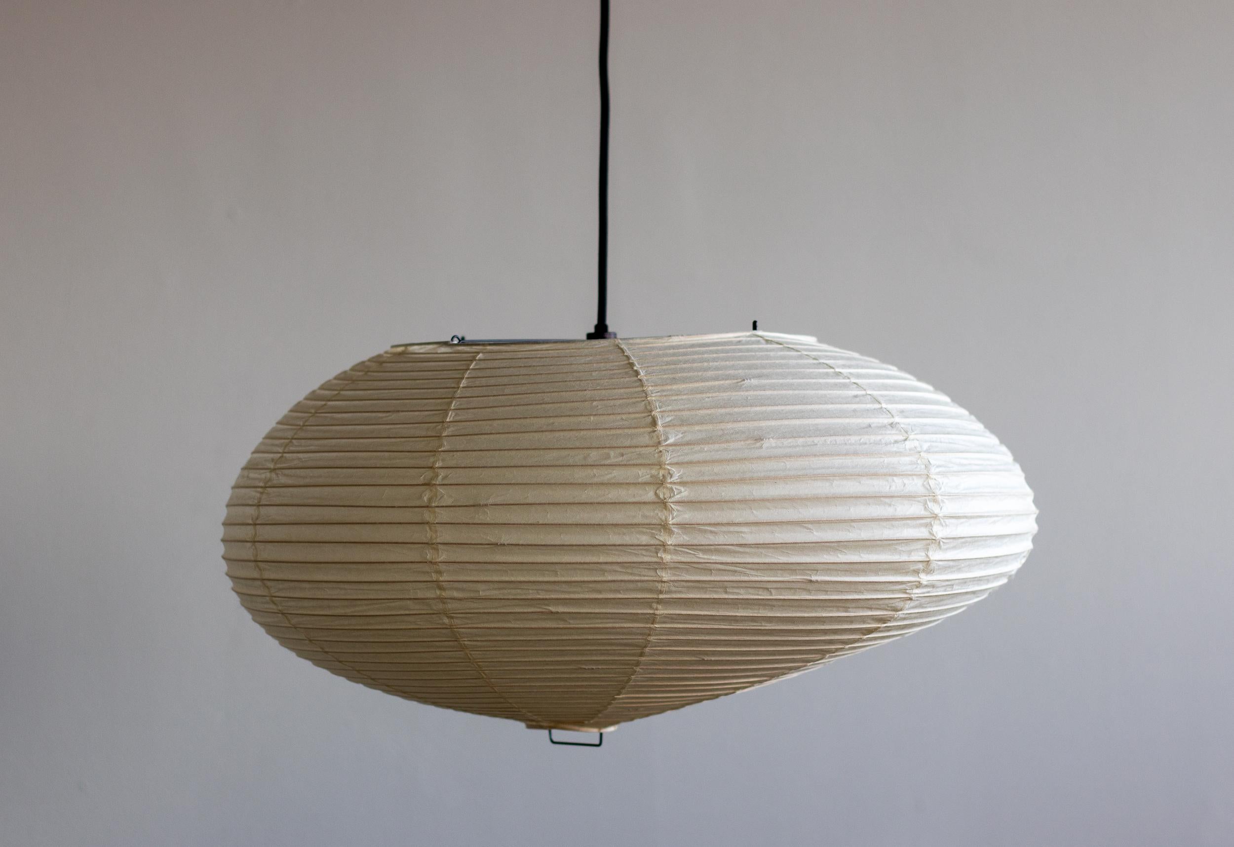 Akari 75D lamp designed by Isamu Noguchi, 1951. Manufactured by Ozeki & Co. in Japan. 
Bambu structure covered by washi paper. Wired for U.S. standards. 
Recent version, new cord and canopy from Noguchi Museum. 
This fixture has one socket. We