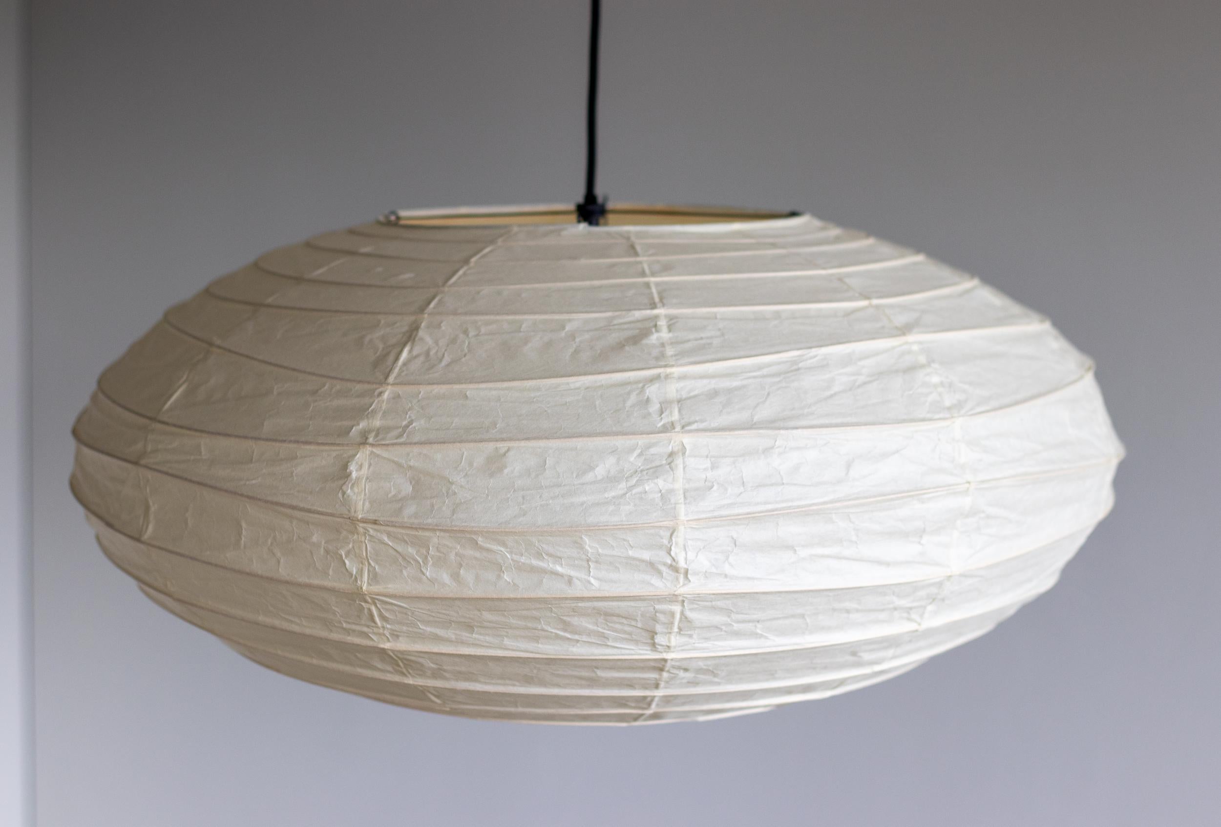 Akari 70N lamp designed by Isamu Noguchi, 1951. Manufactured by Ozeki & Co. in Japan. 
Bambu structure covered by washi paper. Wired for U.S. standards. 
New cord and black enameled steel canopy from Noguchi Museum. 
This fixture has one socket.
