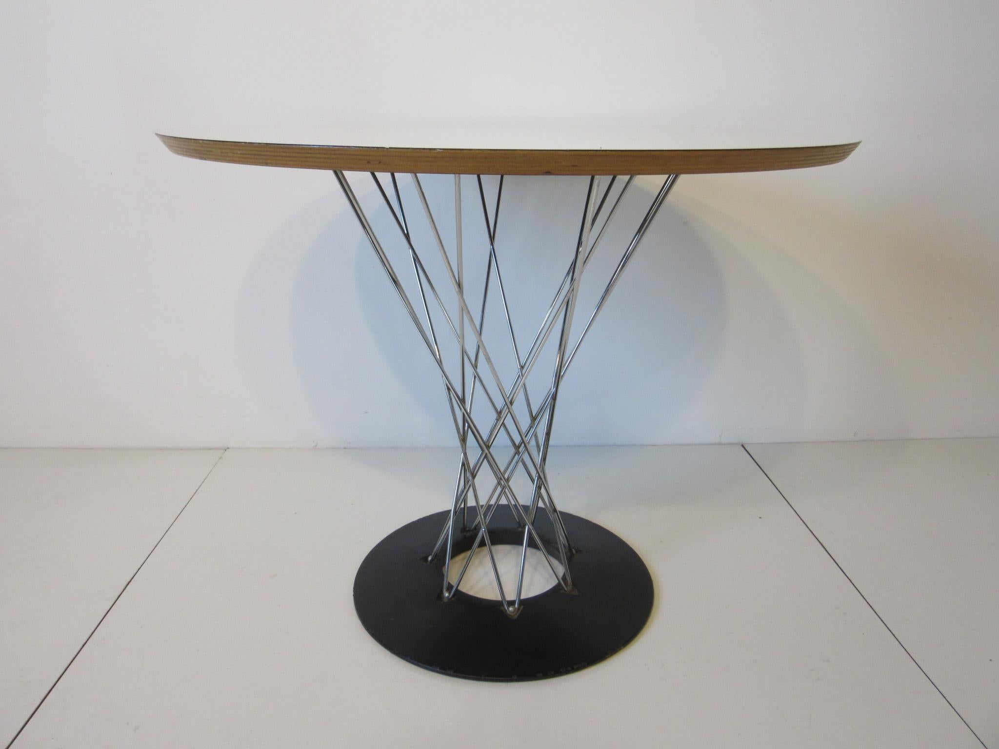 A smaller sized Noguchi Cyclone cafe sized table with white formica top, chromed crossed wire pedestal and satin black steel base. Great size for a eat in kitchen or small apartment retains the original manufactures label by Knoll Associates Inc.