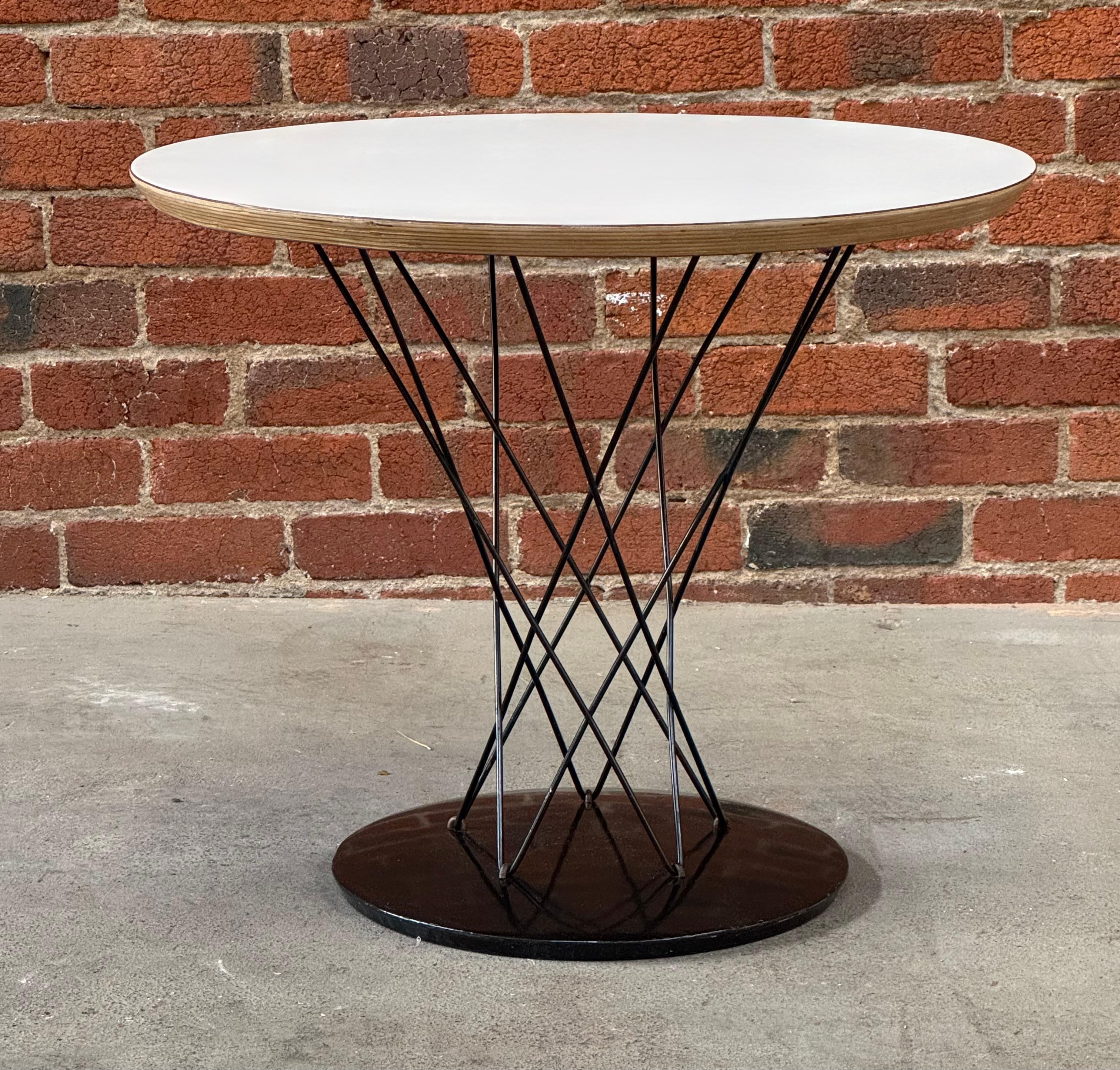 Tavolino per bambini di produzione Isamu Noguchi degli anni '60 con piano in laminato bianco,  aste laccate nere e una base in ghisa con finitura in porcellana nera. La parte inferiore della base è numerata 87.