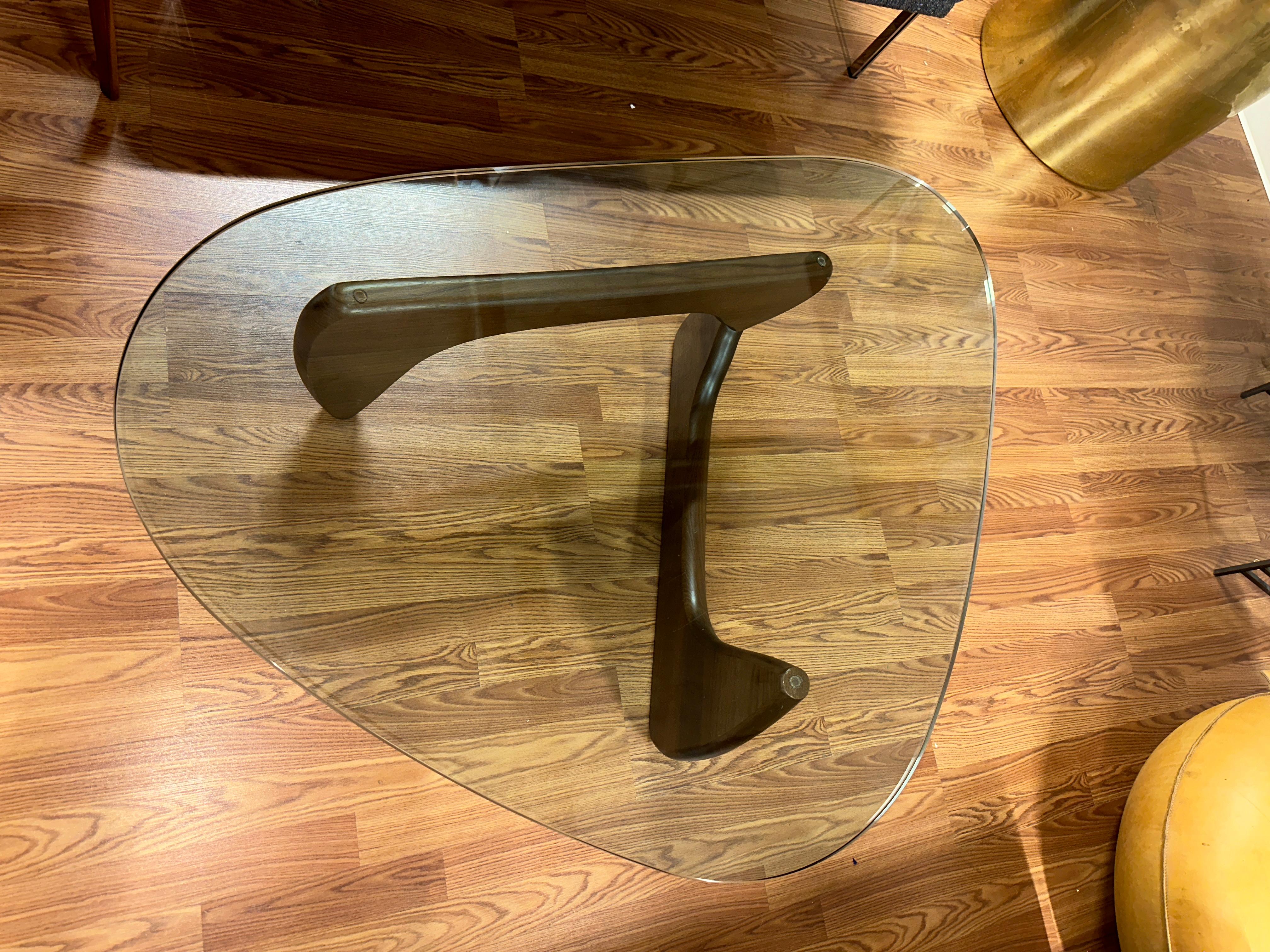 An Isamu Noguchi designed coffee table manufactured by Herman Miller with the more desirable Walnut Base. The piece is fully labeled and signed not eh edge of the glass. This iconic design works in any mid century setting. The table is in good