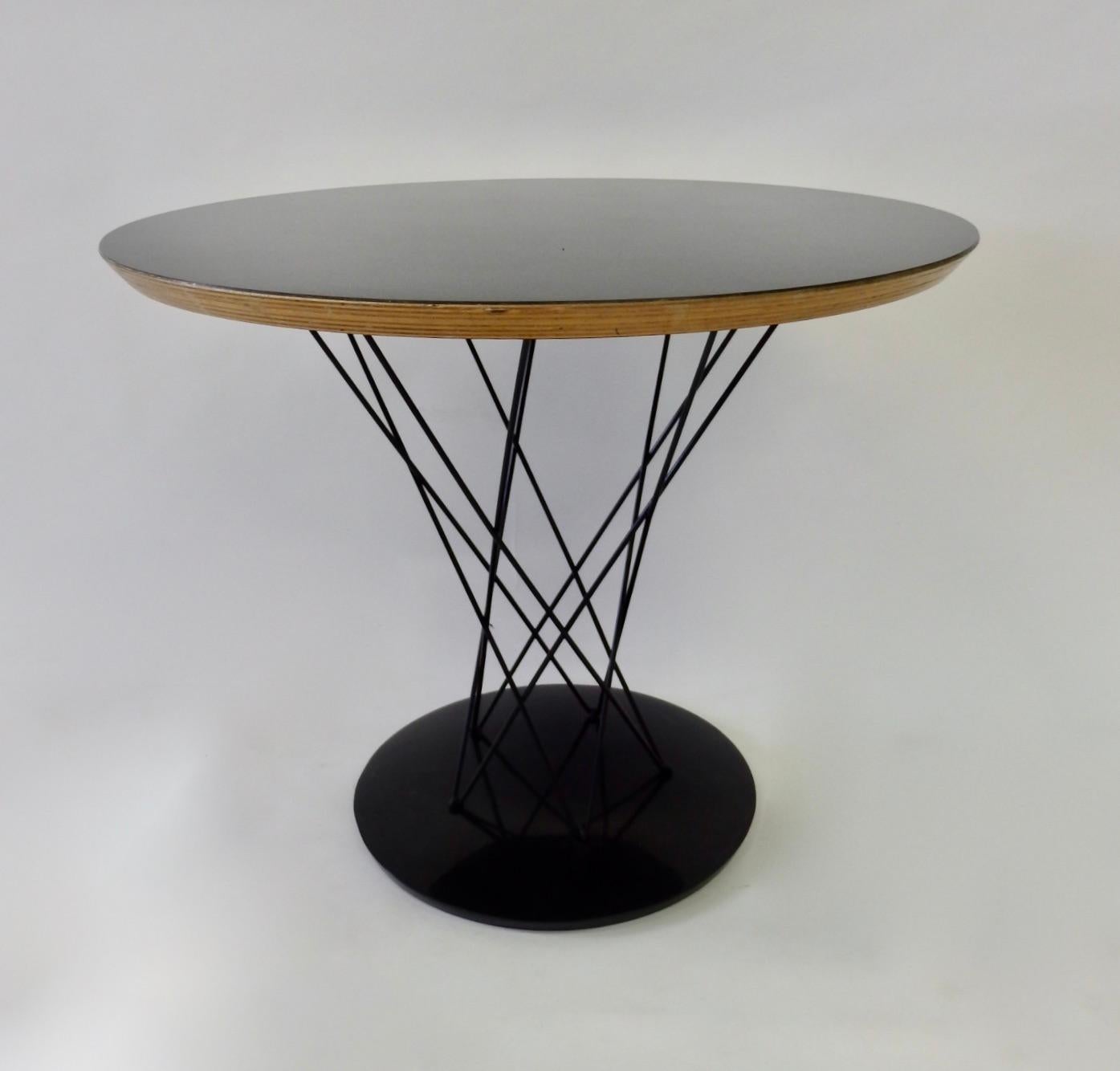 Cyclone occasional table designed by Isamu Noguchi for Knoll. Round cast iron base holds wire cyclone base supporting black laminate top. Partial Knoll label remains.