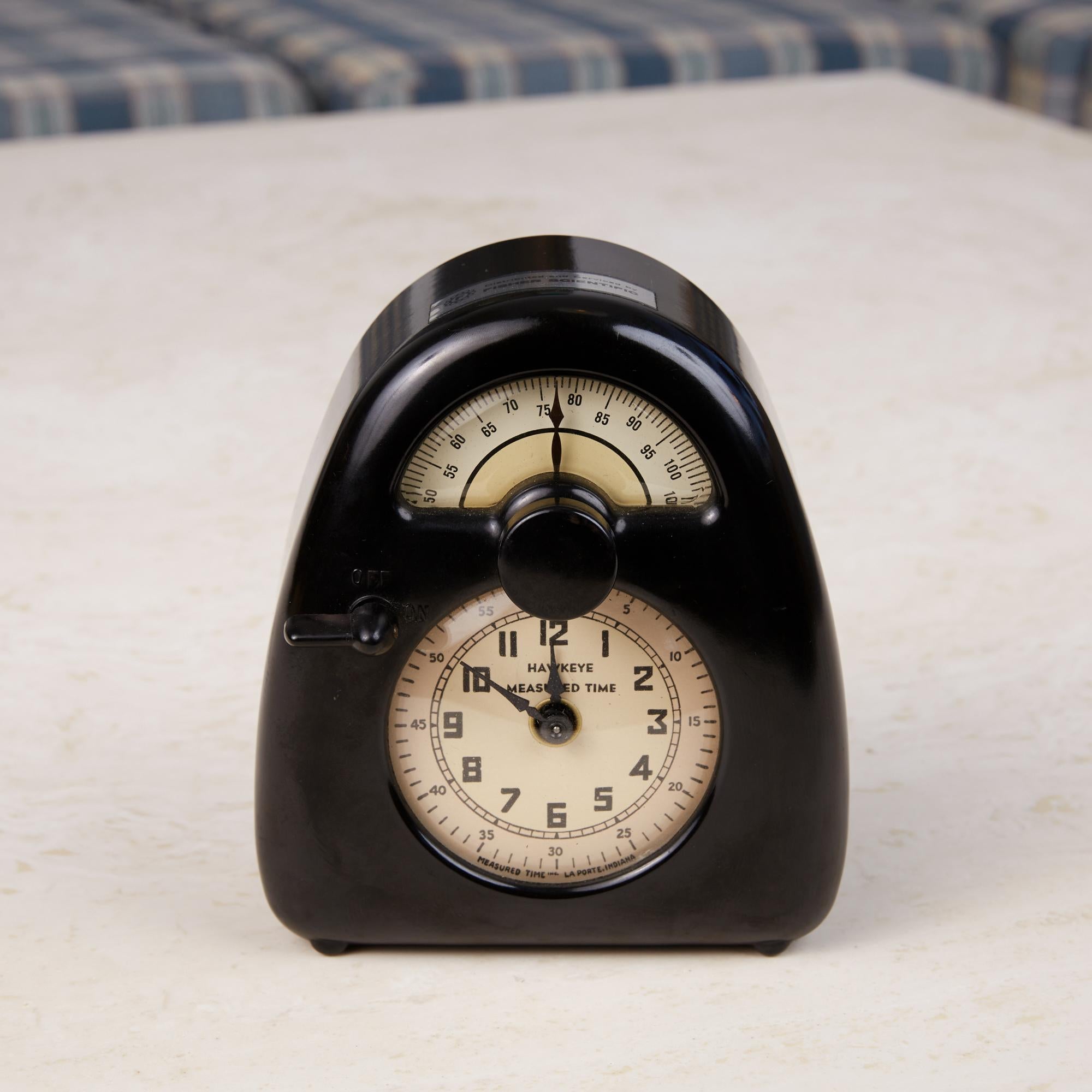 Hawkeye kitchen timer and clock by Isamu Noguchi, c.1930s. This 1932 design was Isamu Noguchi's first commercial design. The pieces features an arched black Bakelite frame that houses a clock in the lower portion and a 120 minute timer in the top