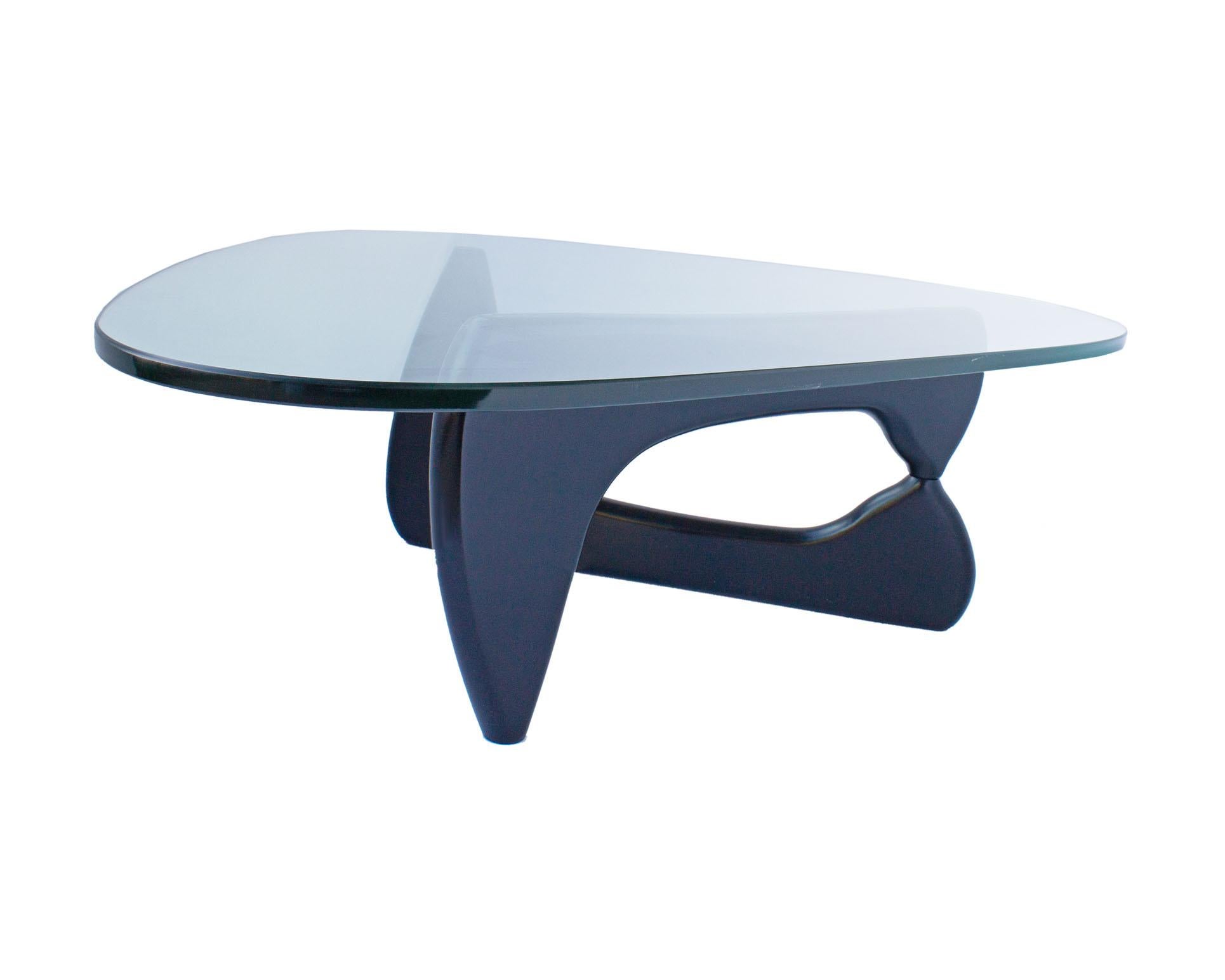 A Noguchi coffee table designed by the American designer Isamu Noguchi (1904-1988) for Herman Miller. This iconic table has a triangular glass top that rests on a black wooden base that scissors open. Originally designed in 1948, this table was