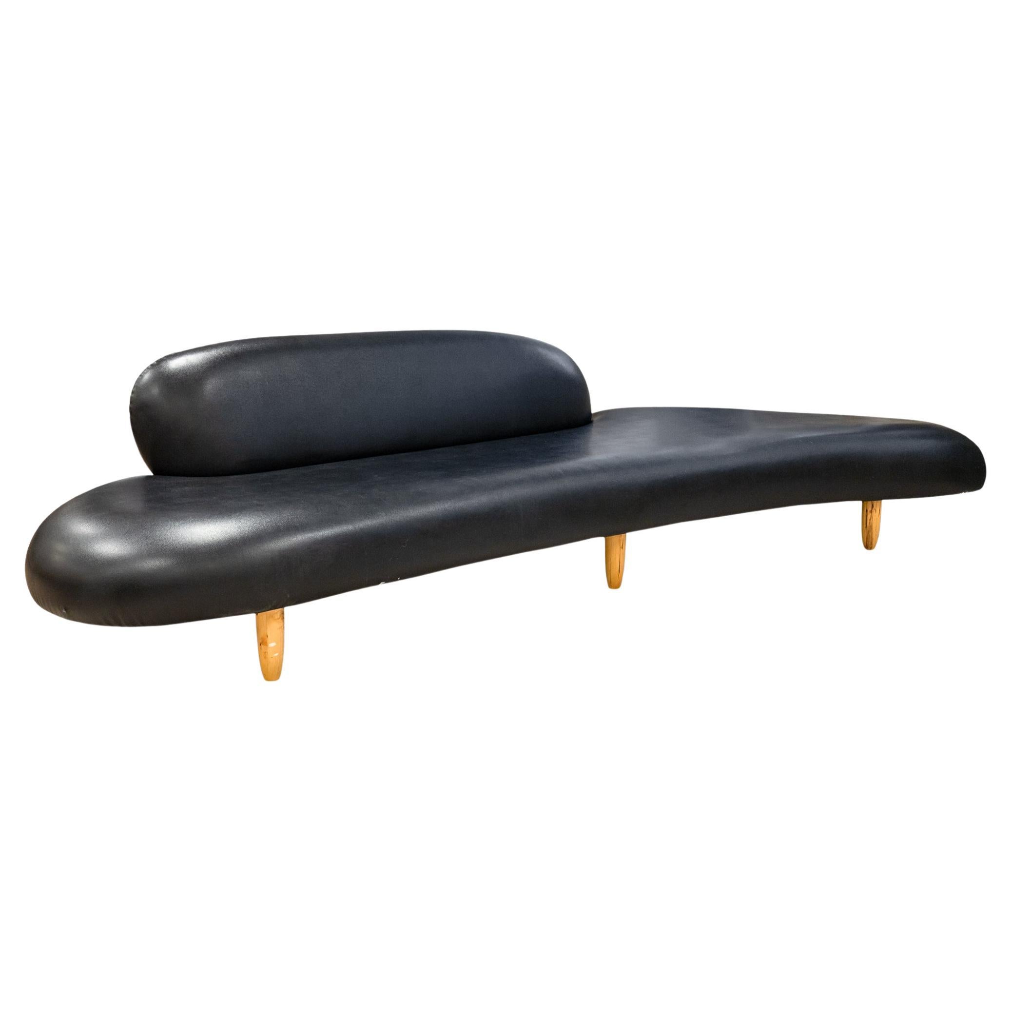 An Isamu Noguchi style freeform sofa and ottoman attributed to Vitra. A stunning piece of design history by legendary artist and designer Isamu Noguchi. This freeform sofa features a rich black leather upholstery, and a round beechwood set of legs