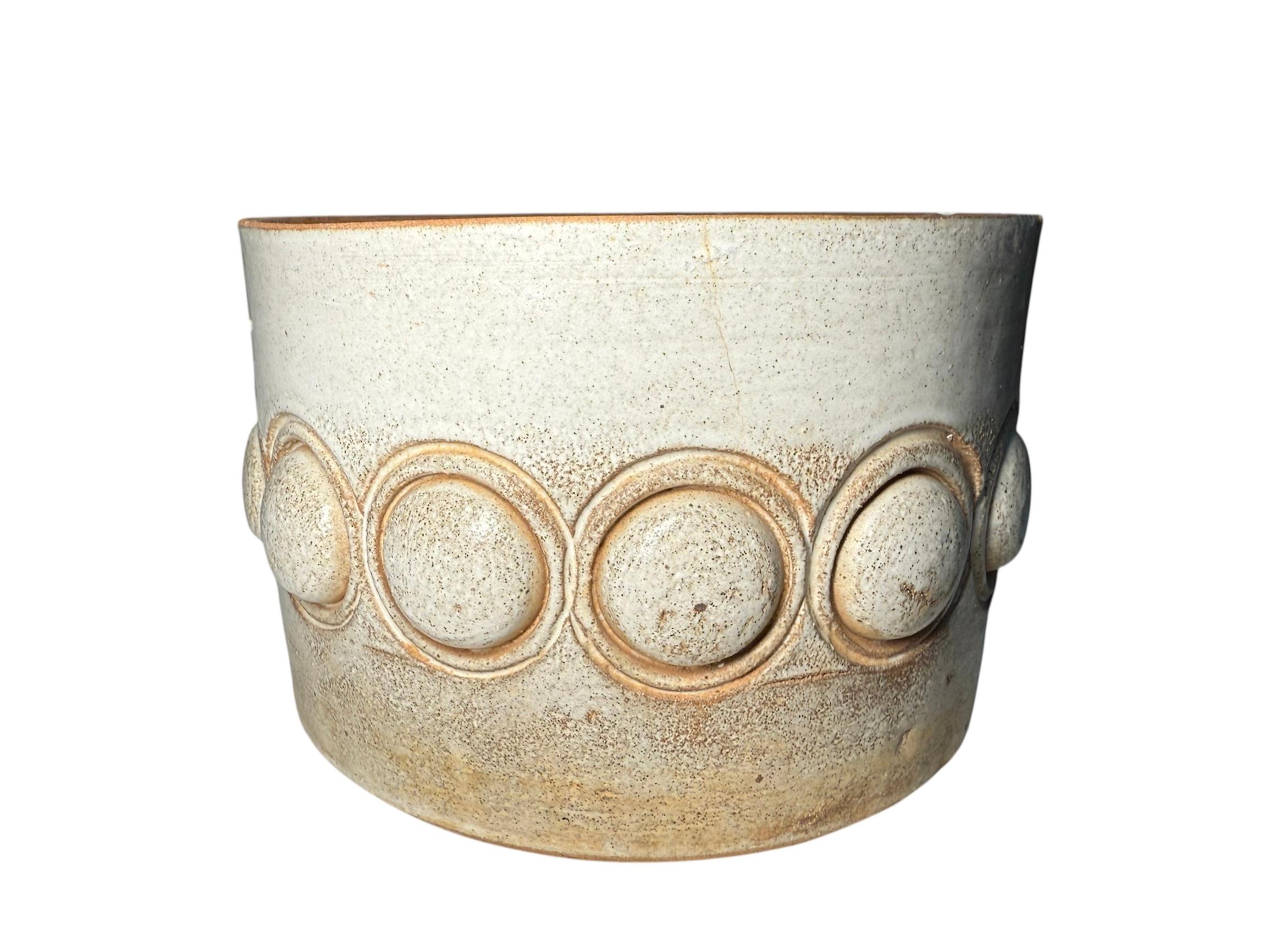 This is an Isla del Sol Puerto Rican Stoneware Planter. It depicts a small bucket shaped planter hand painted pearly white color and decorated with a row of half spheres in the center. This Puerto Rican Pottery Workshop ( 1962- 1970’s ) is renowned