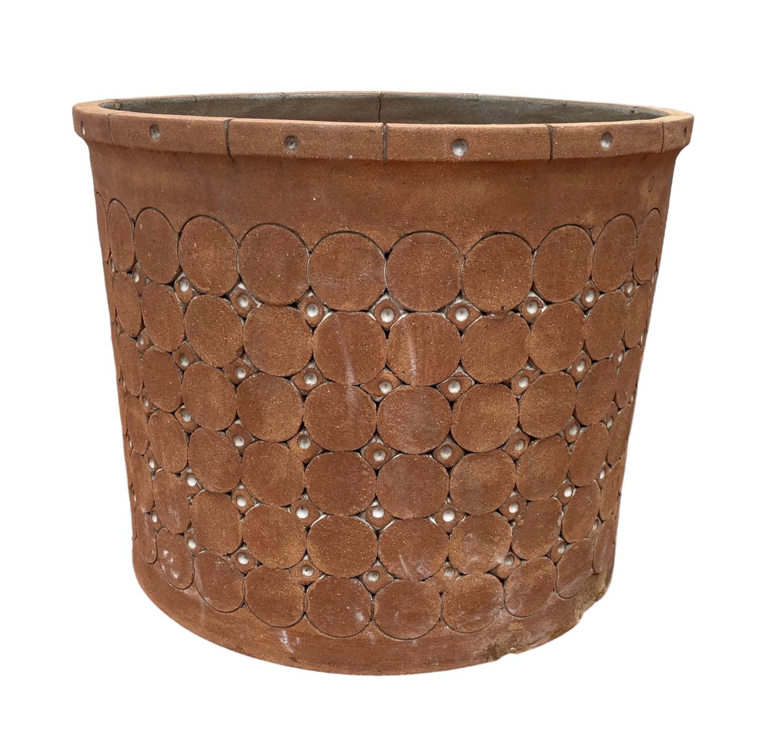 This is an Isla Del Sol Puerto Rican huge and heavy stoneware round planter. It is dark sand color and adorned with six rows of large circles alternated by five rows of small circles. This planter weights about 60 pounds.