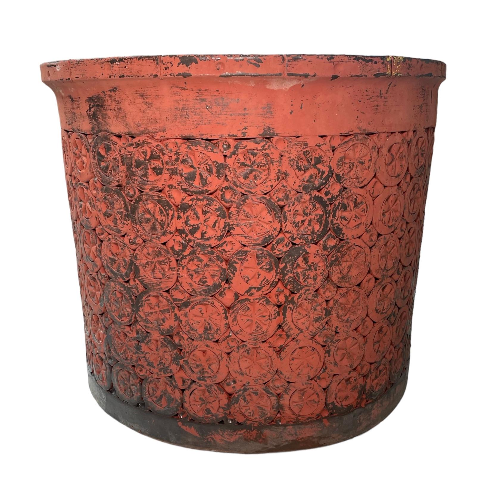 This is a Puerto Rican, Isla Del Sol Stoneware Planter. It depicts a heavy orange round planter decorated with six rows of circles adorned in the center with stars. These rows are alternated with six rows of squares with concave hemispheric centers.