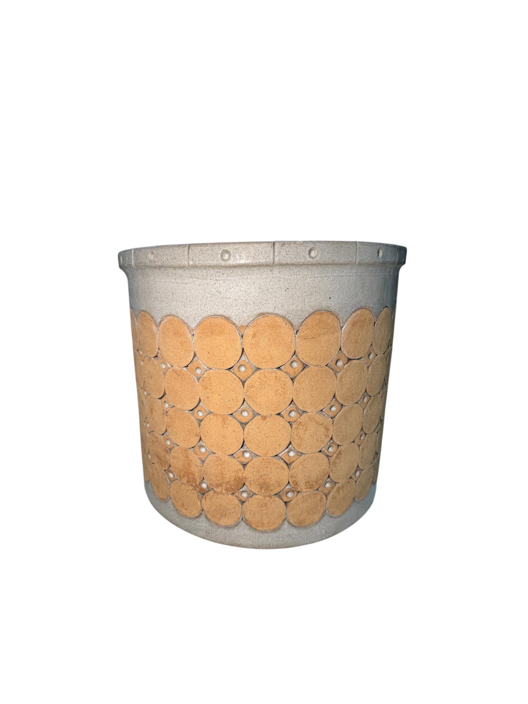 This is an Isla Del Sol Puerto Rican huge and heavy stoneware round planter. It depicts a light pearly and brick color. It is adorned with five rows of large circles alternated by 4 rows of small circles. This planter weights about 60 pounds. This