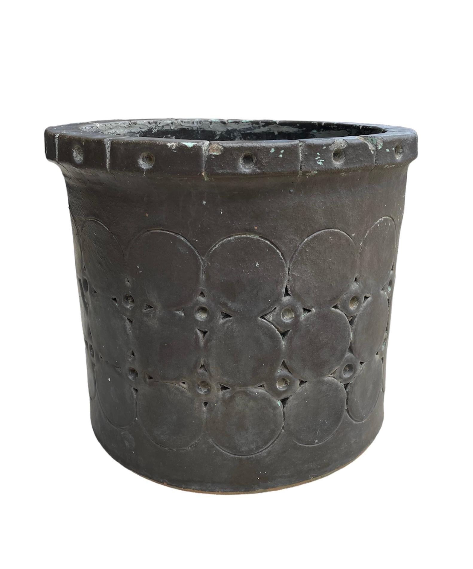 This is an Isla Del Sol Puerto Ricans Stoneware Planter. It depicts a round and heavy planter painted black. It is also adorned with three rows of large circles alternated with two rows of hollow small circles. The upper border is also decorated