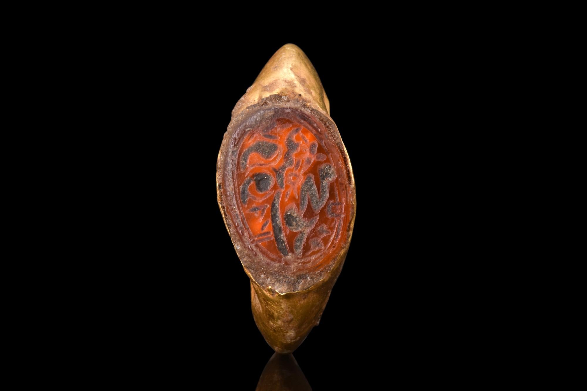 A Sasanian gold ring adorned with a carnelian intaglio featuring masterful calligraphy. The carnelian intaglio in this particular ring is a testament to the mastery of early Islamic calligraphy, with its delicate curves and graceful lines forming a