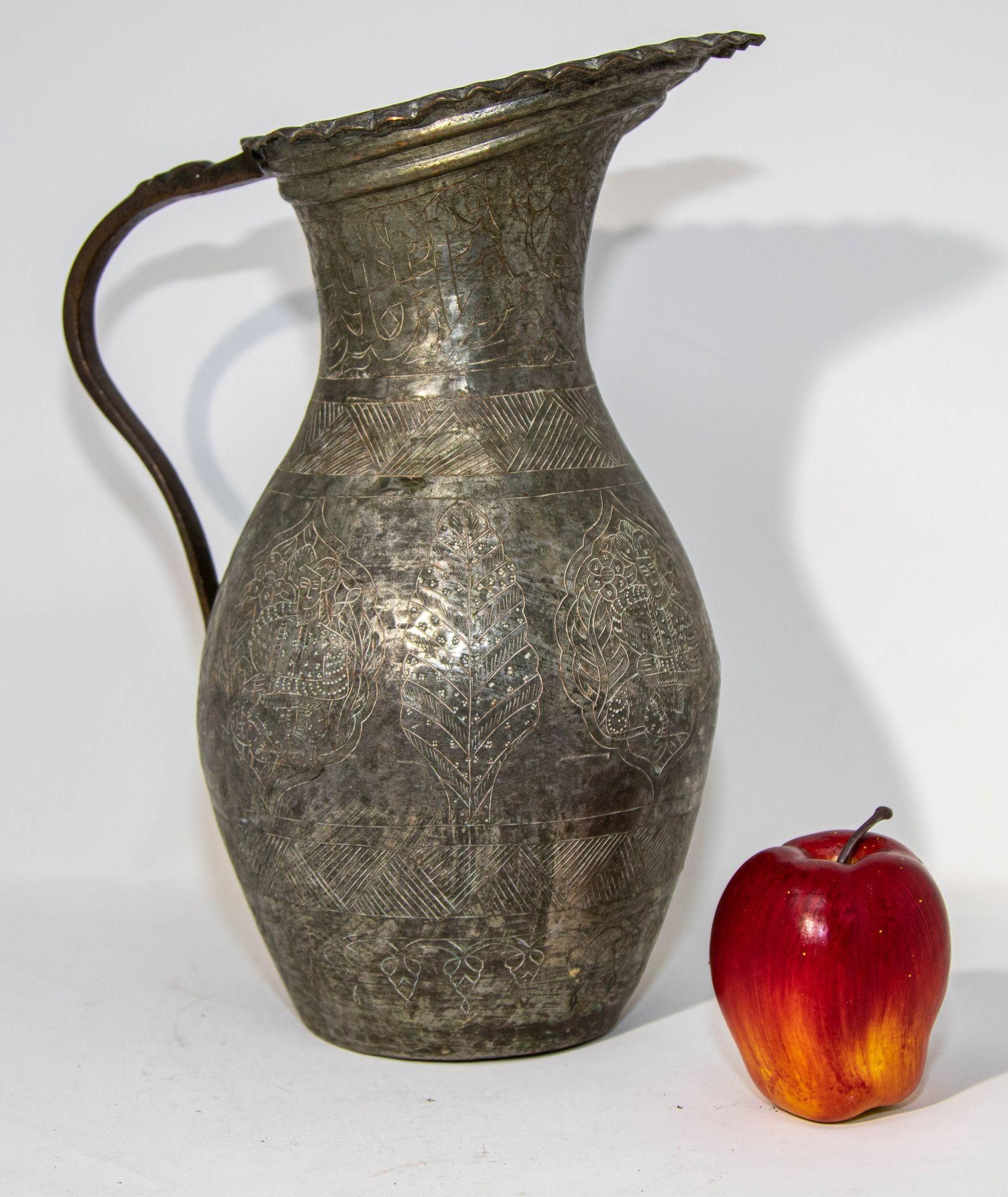 Antique 19th century Middle Eastern Persian Qajar Dynasty ( 1785-1924) tinned copper pitcher.
The teardrop form ruffled mouth with a flat hand wrought handle, over a neck decorated with hand chased figures and geometric designs.
Nice decorative old