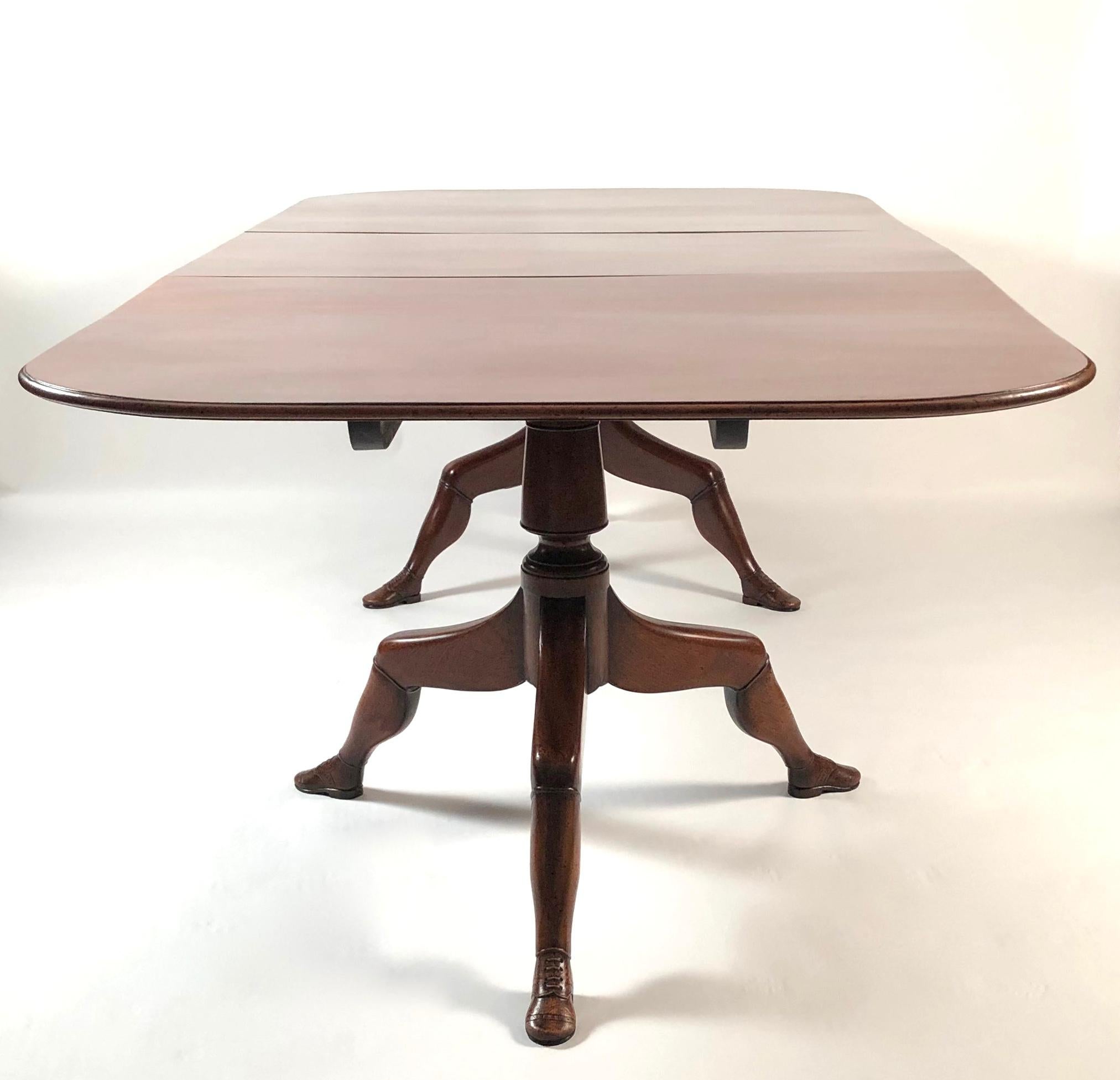 A fine quality and unusual mahogany extension dining table from the Isle of Man, with rich, deep color, the rectangular top with rounded corners and bullnose edge, supported by two pedestals raised on tripod legs, carved as human legs wearing carved
