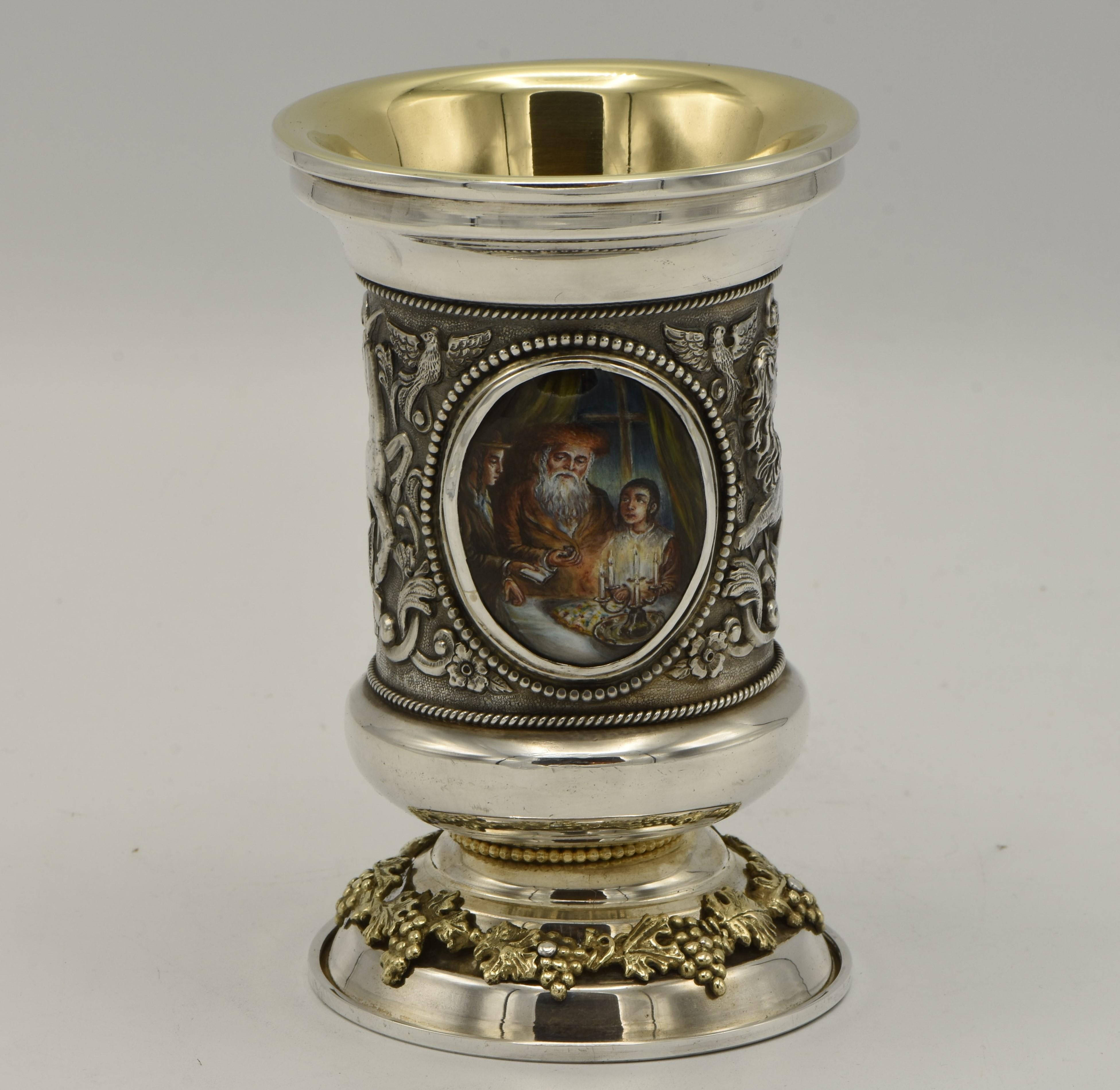 Handmade sterling silver Kiddush Goblet, Y. Chaskelson, Israel, circa 1990.
The goblet is decorated with two colorful hand painted enamel plaques, one depicts mother and daughter blessing on the Shabbat candles, the other plaque depicts father and