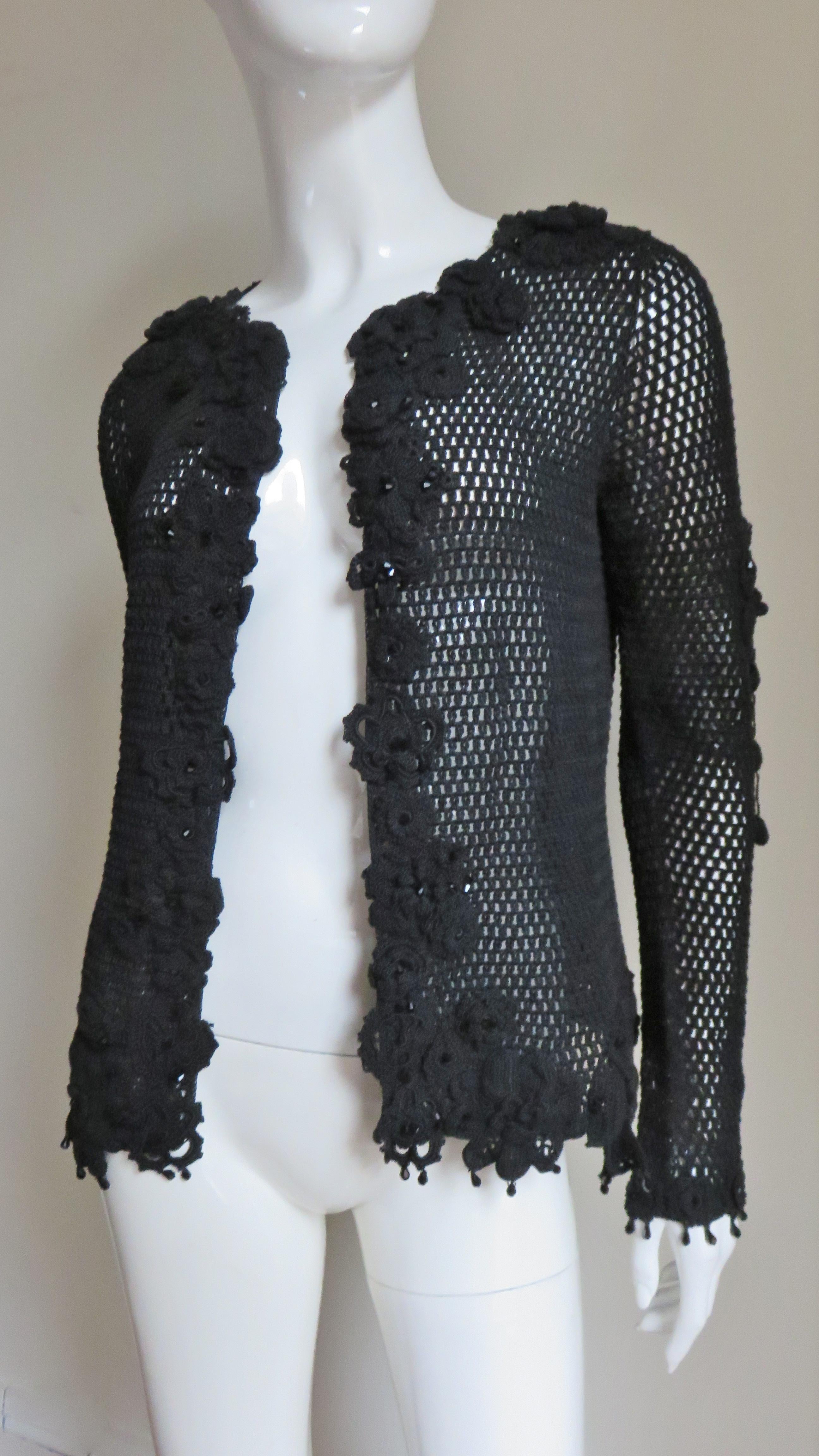 A very pretty black crochet cardigan from Issac Mizrahi. It has long sleeves, applique matching crochet flowers around the neck, front, hem and on the sleeves. There are black glass beads around the hem and cuffs.
Fits sizes Small, Medium.  Marked
