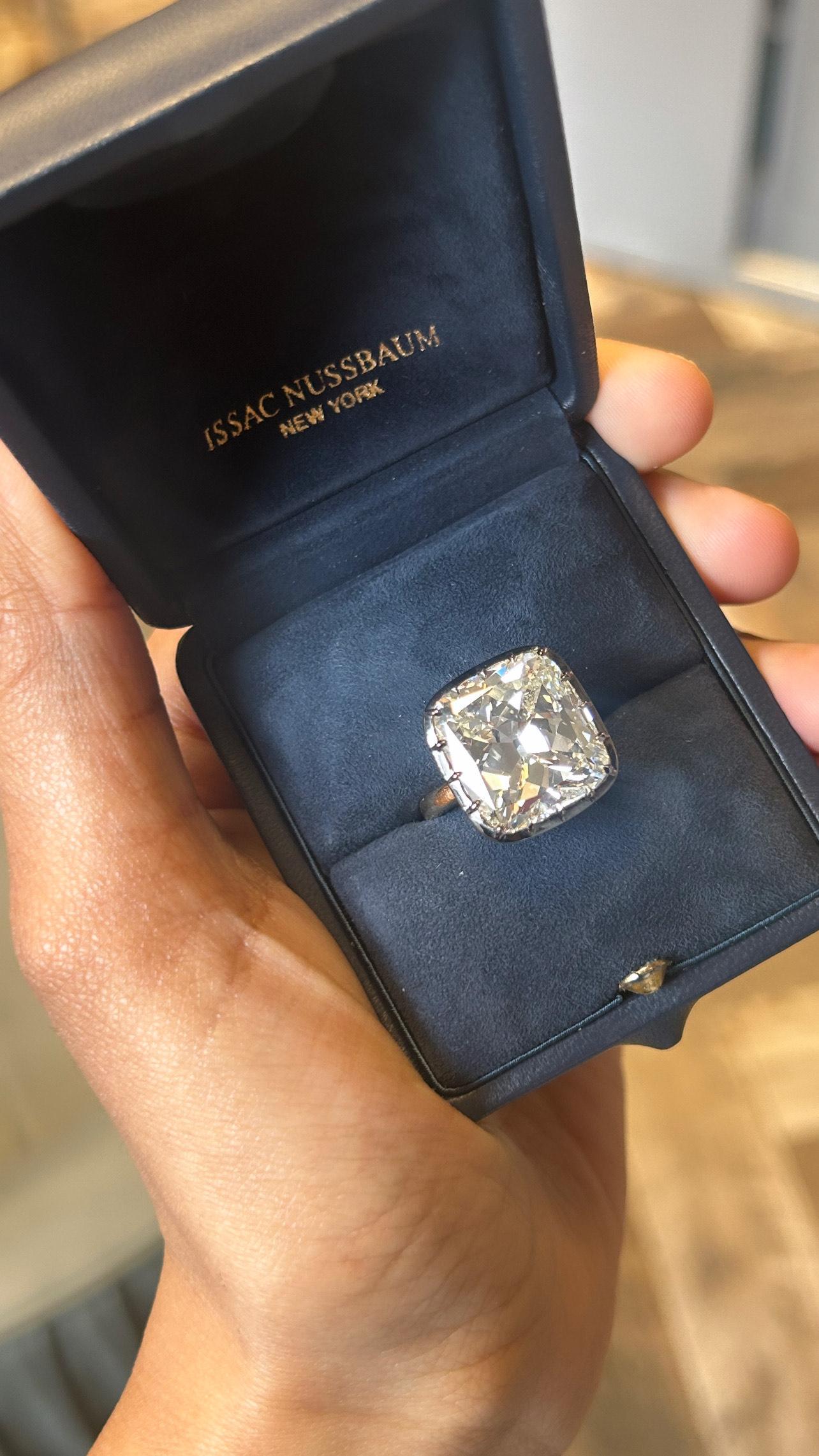 The ring in the image features a large, GIA certified 18K black and yellow gold antique cushion-cut diamond mounted in a simple yet elegant gold band. The diamond is secured by a sixteen-prong (16) setting, allowing the stone to capture and reflect