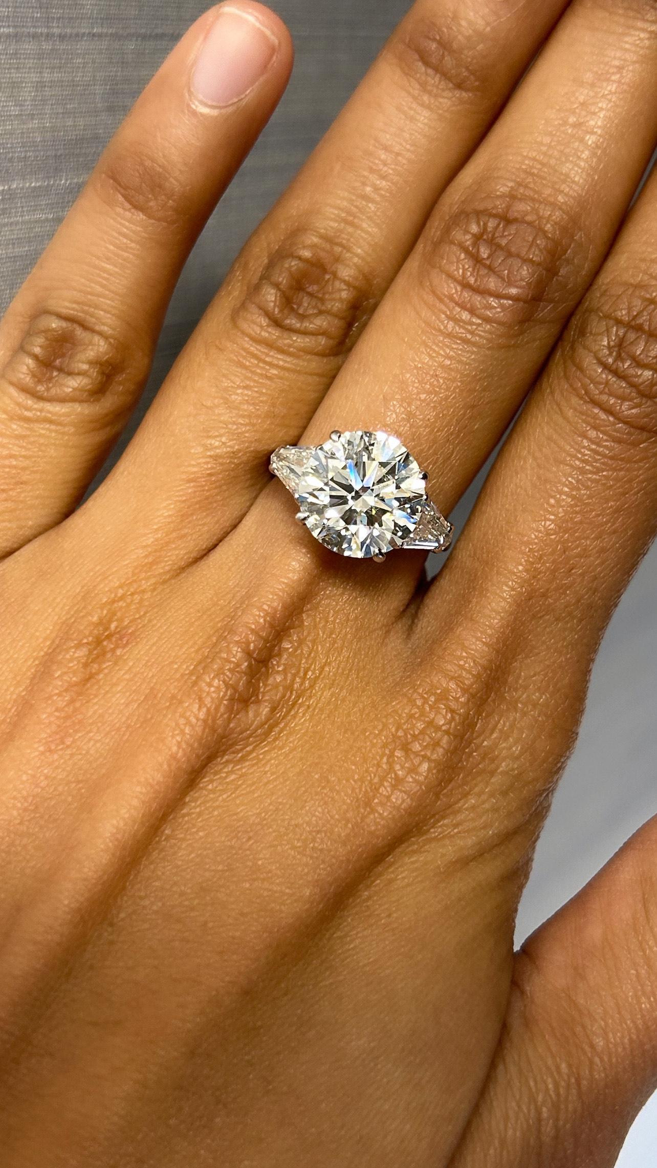 This captivating Gia-certified platinum ring features a striking 6.01-carat round diamond. Flanking the center stone with two rare step-cut bullet shape dazzling  side diamonds, totaling approximately 1.00 carat, which enhance the overall brilliance