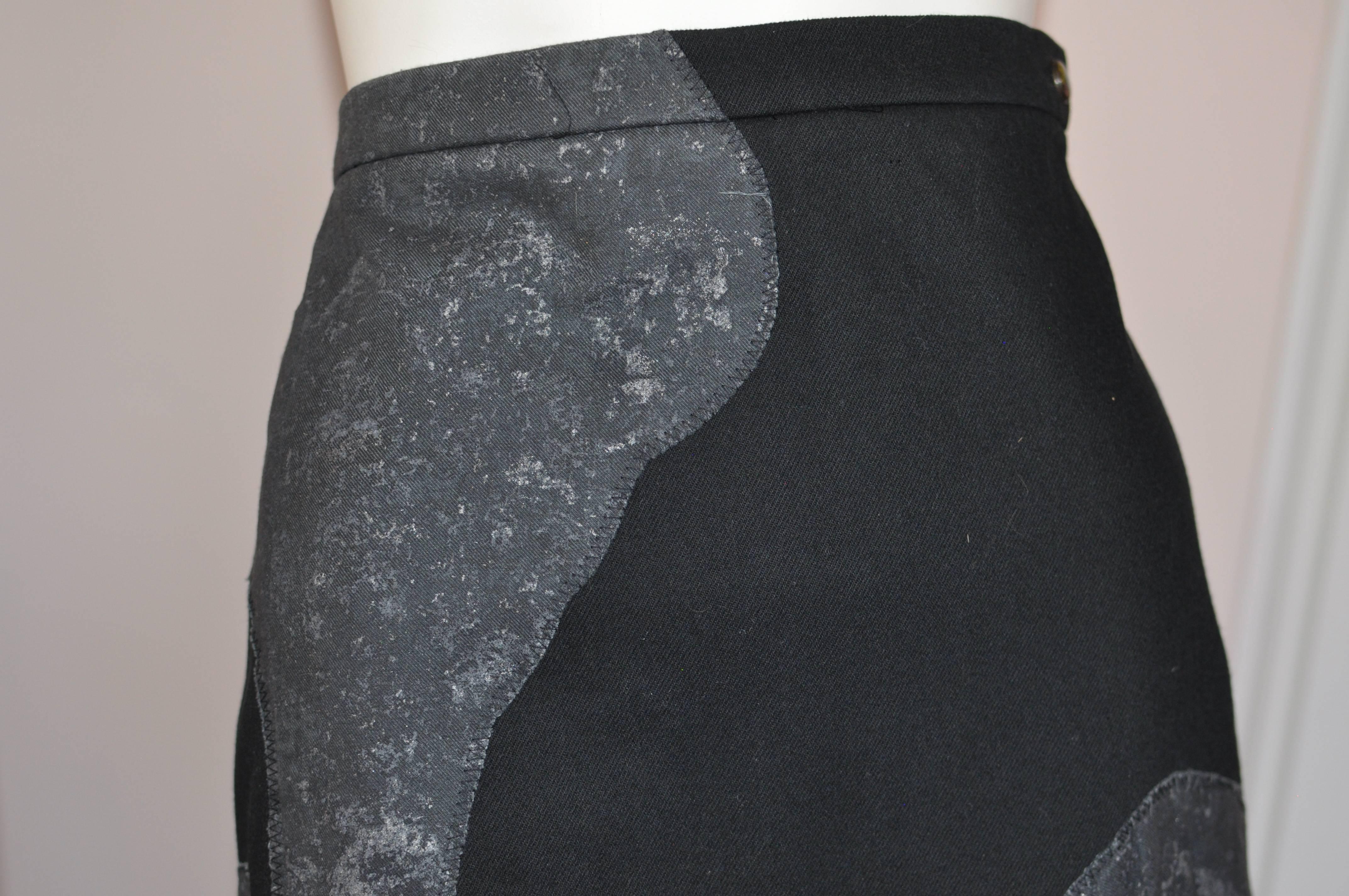 This high waisted skirt is fashioned of a heavy jean like weight cotton in black with grey stitched patches covered in silver grey flakes. The hems are uneven (kerchief), and have an unfinished look, as many of the Miyake clothing. Closure is with a