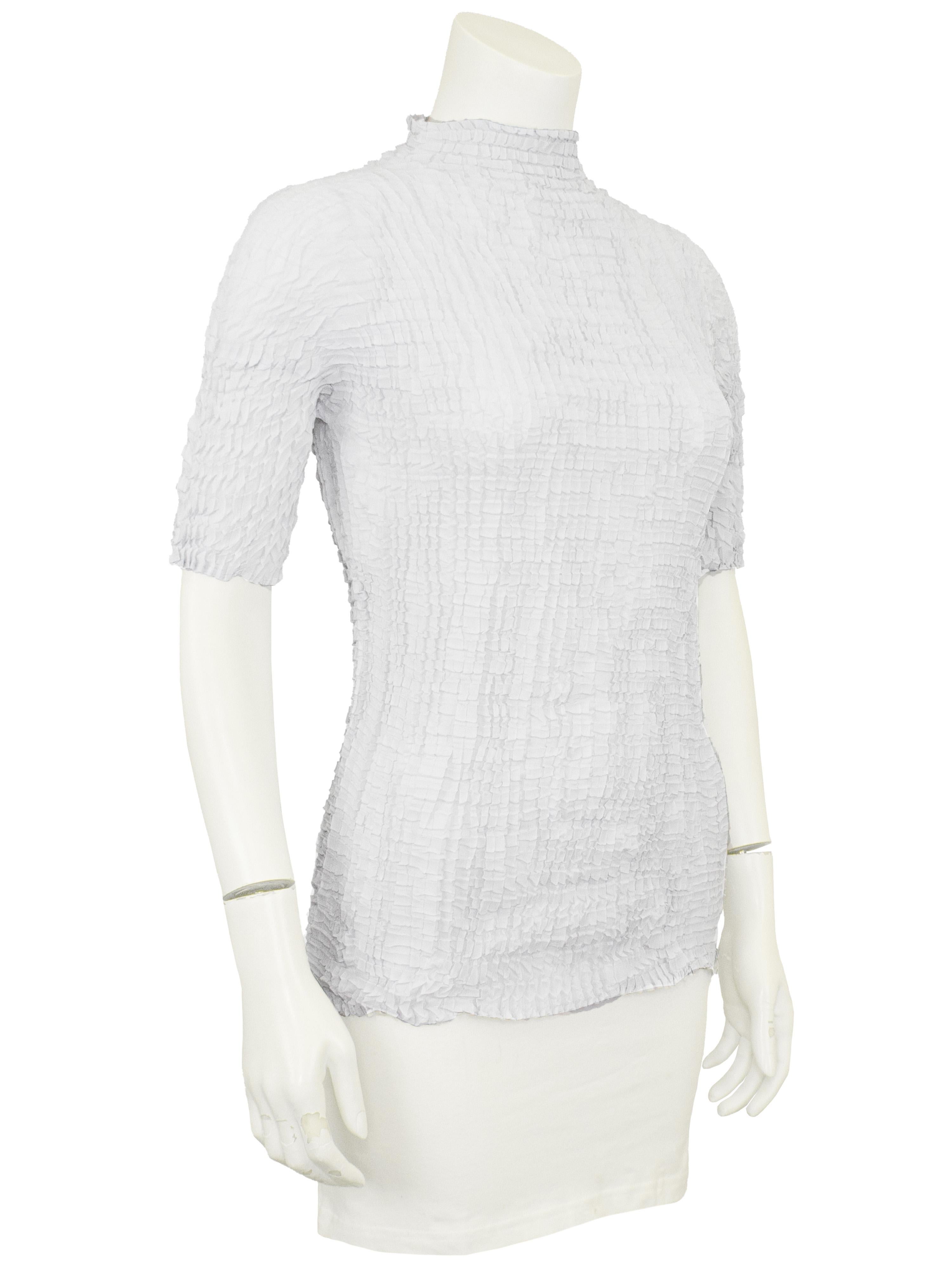 Questo top a maniche corte degli anni '90 dà un'impressione di freschezza con le sue linee di pieghe casuali, caratterizzate da una finitura in chiffon semitrasparente e da una fine plissettatura a mano. Un capo stabile della stagione di Issey