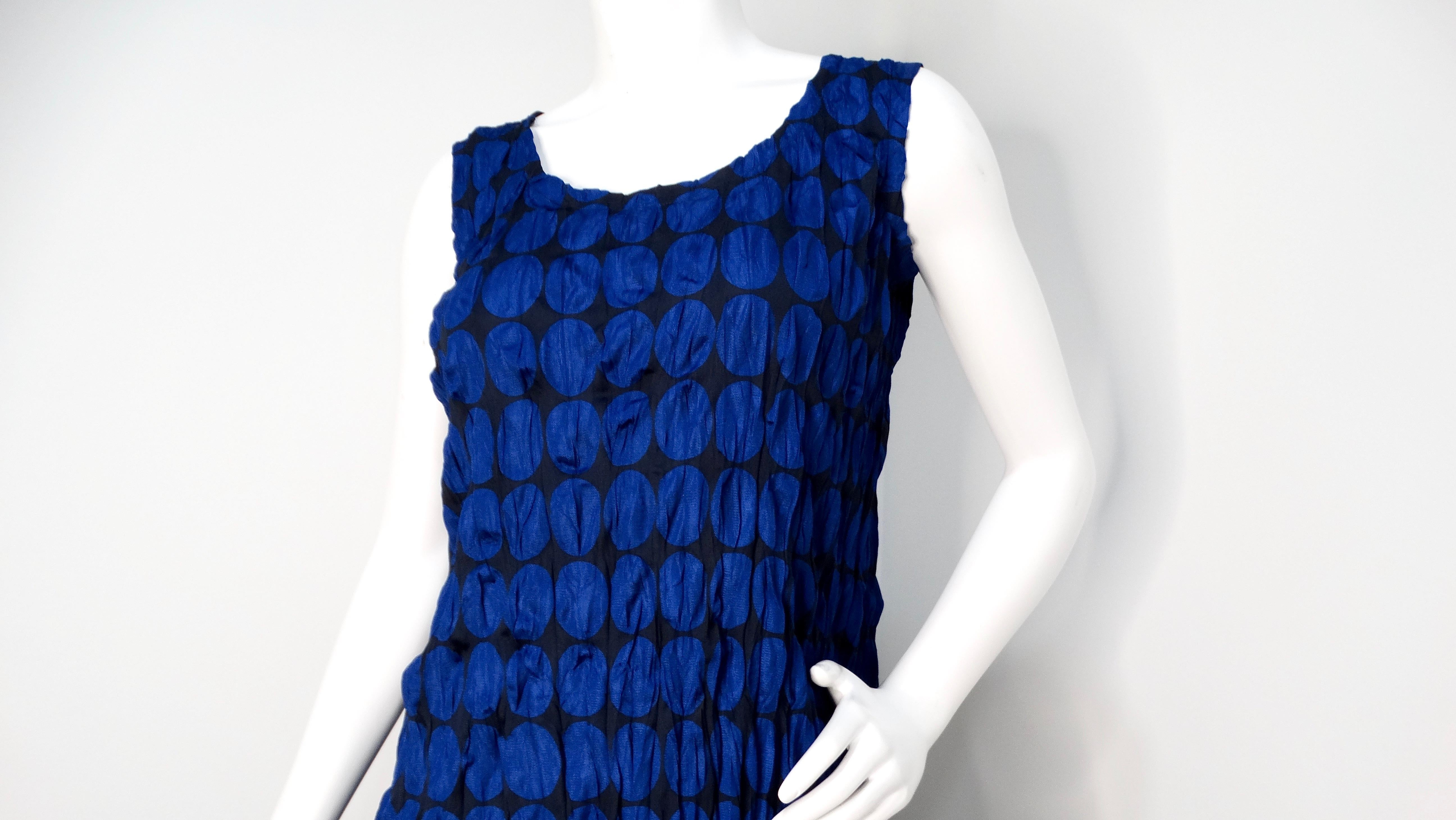 El Vestido sin Mangas de Lunares Azul Oscuro Pleats Please de Issey Miyake 1990 es una pieza impresionante que ejemplifica el característico enfoque del diseñador hacia el tejido y la forma. Sobre una elegante base negra, el vestido está adornado