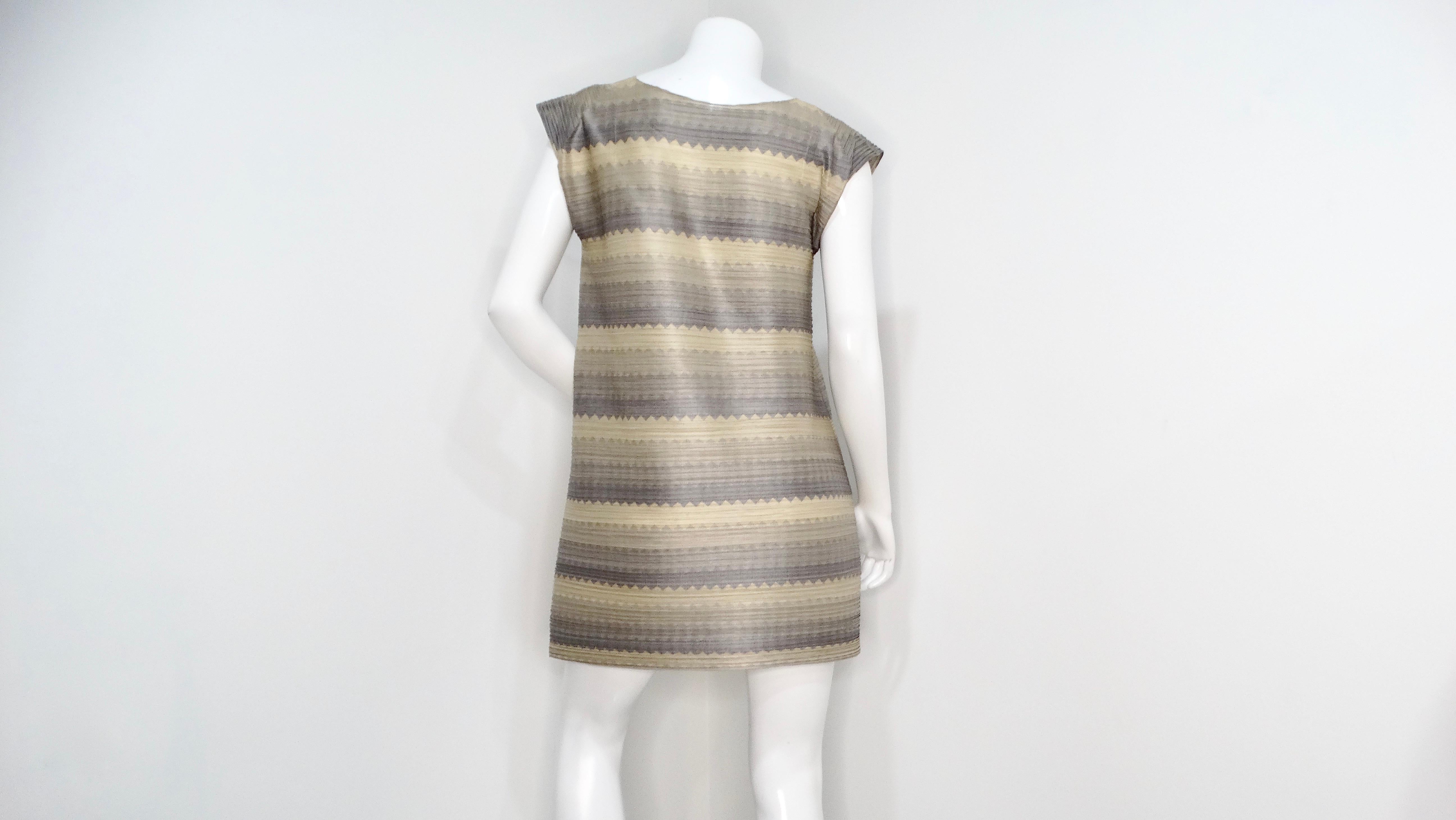 The Issey Miyake 1990s Pleats Please Striped Earthy Tones Tunic Blouse is a stunning piece that effortlessly merges bold design with versatile styling options. Featuring a captivating zigzag stripe pattern paired with horizontal pleats, this