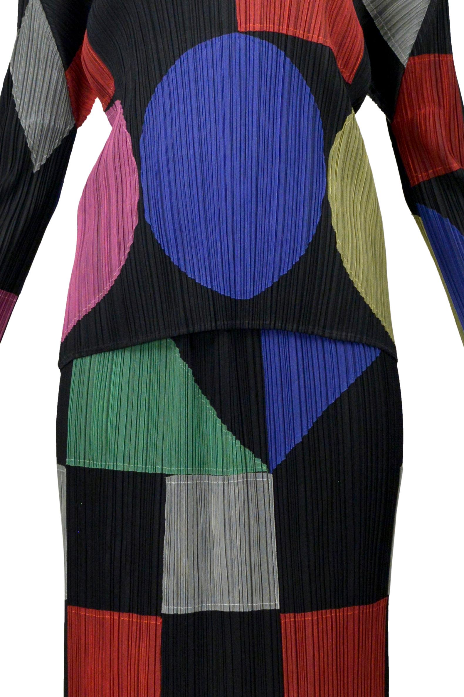 Resurrection Vintage se complace en ofrecer un conjunto vintage de Issey Miyake, Pleats Please, que incluye coloridos apliques geométricos en la parte superior y en la falda, una parte superior de manga larga, aberturas laterales en la falda y una