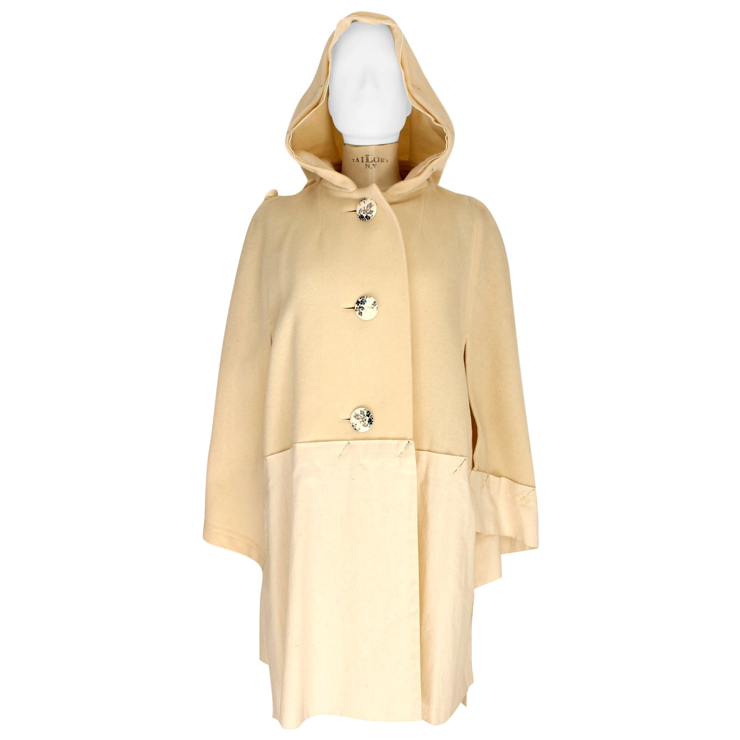 Issey Miyake coat for women vintage 90s. Model cape with wide sleeves and hood, color beige with silver-colored details, closure with large spotted buttons. Dressmaker Needles Silver Cotton Details. Composition 90% wool 10% nylon. Made in Japan.