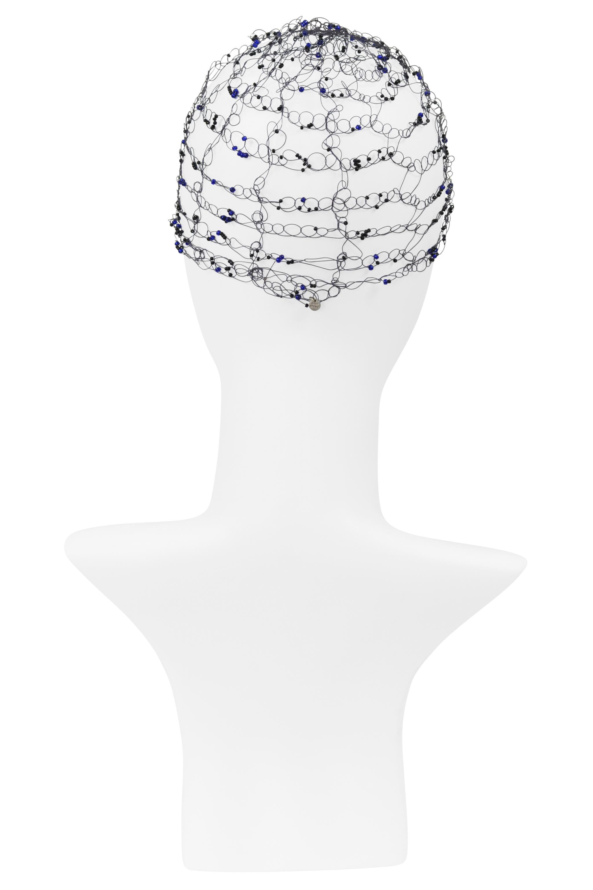 Resurrection Vintage freut sich, ein schwarzes Haarnetz von Issey Miyake mit blauen Perlen präsentieren zu können. Das Haarnetz ist mit kleinen schwarzen und blauen Perlen durchwebt, hat ein offenes Netzmuster und einen kleinen silbernen 