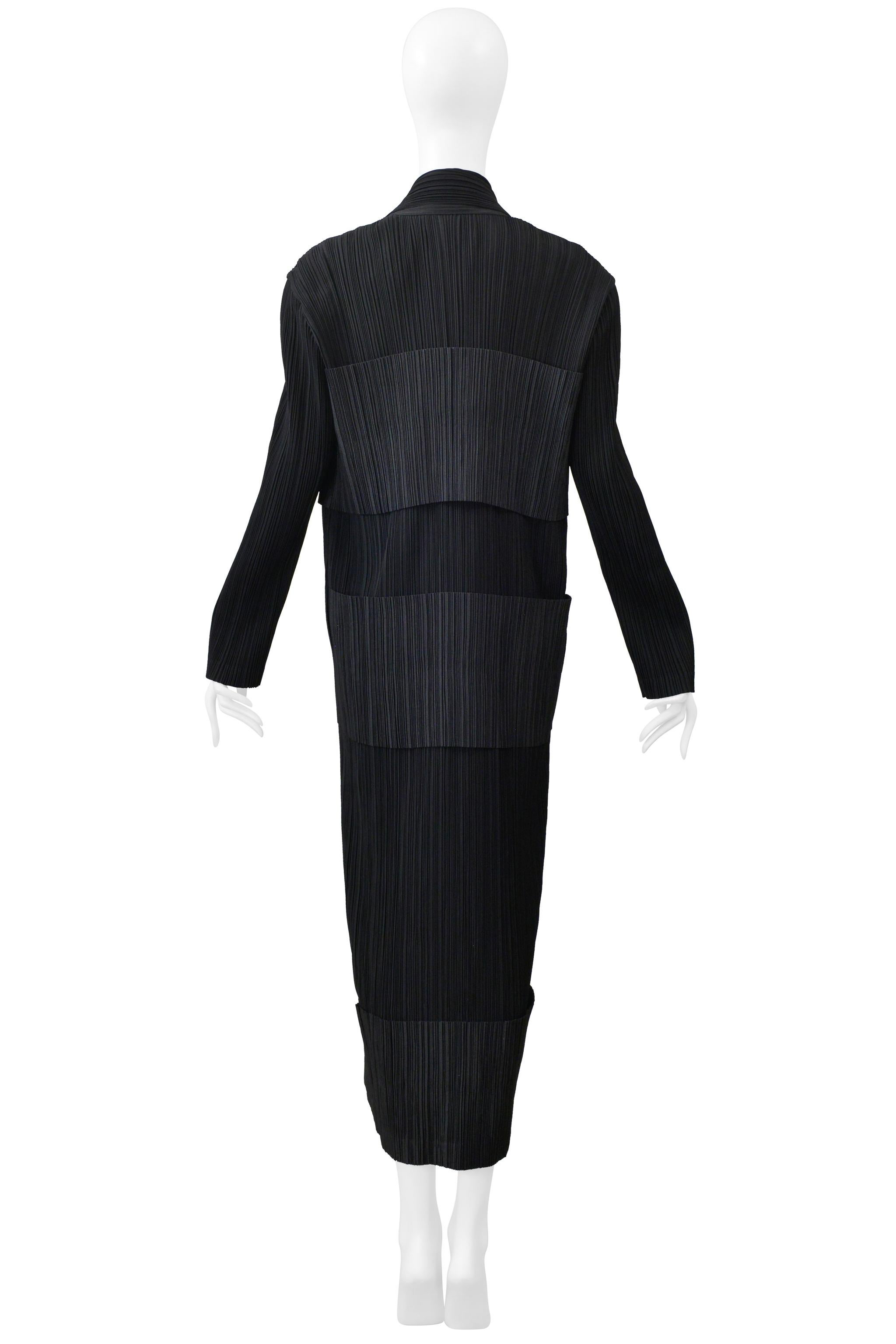 Resurrection Vintage a le plaisir de vous présenter une robe plissée de smoking noir vintage Issey Miyake de la collection 1998-1999, avec une encolure en collier, des fermetures à boutons de type smoking, des panneaux superposés, des manches