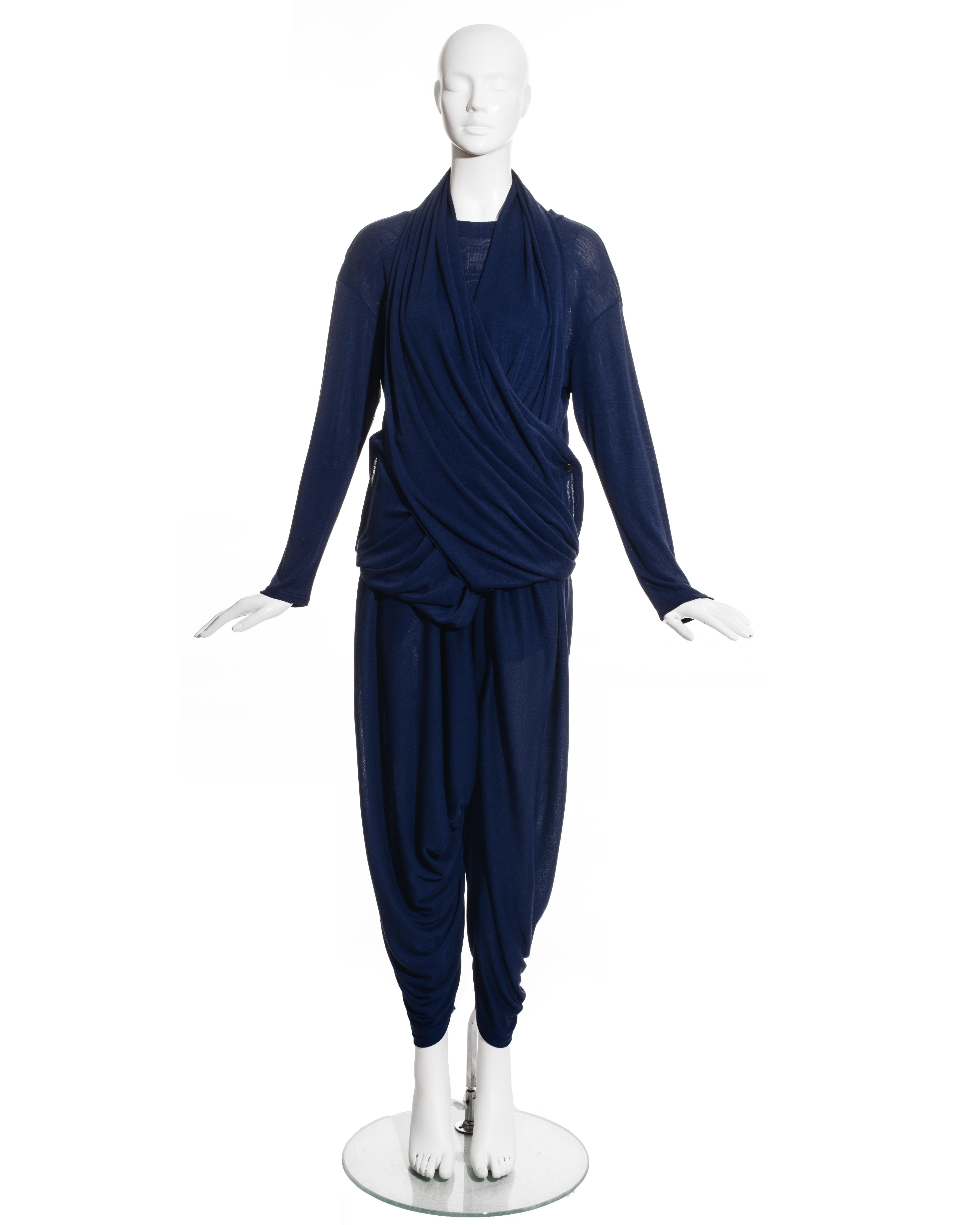 Issey Miyake Permanente, blue rayon knitted pant suit comprising: sweater with two long panels which drape around the toros fastening with two buttons on the hips, harem style pants with elastic waistband.

Issey Miyake PERMANENTE was launched in