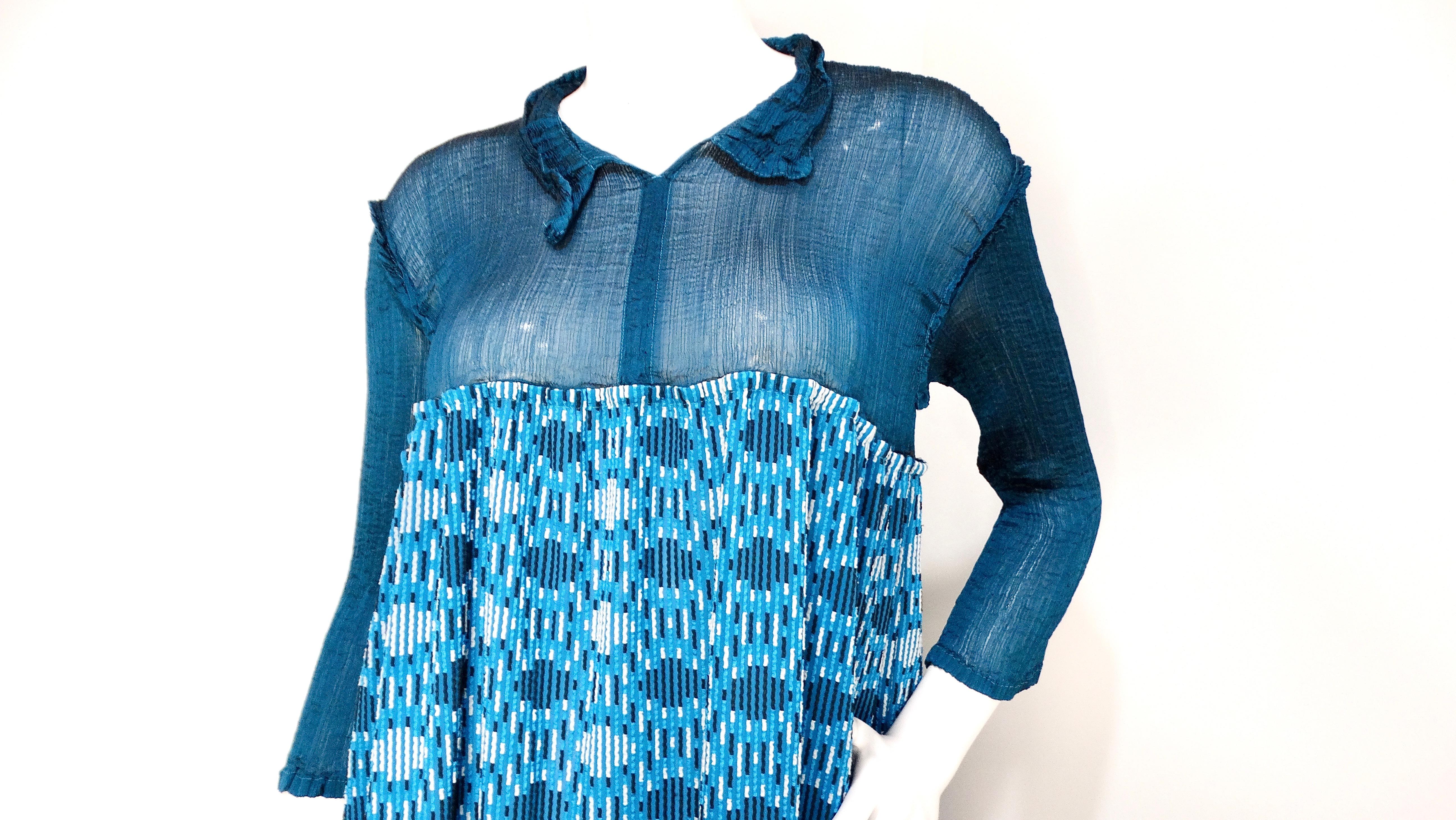 The Issey Miyake 2000s Turquoise Pattern Long-Sleeve Babydoll Dress is a delightful blend of color and retro charm. The top third of the dress boasts a vibrant turquoise hue with a classic collar, creating a polished yet playful look. The bottom