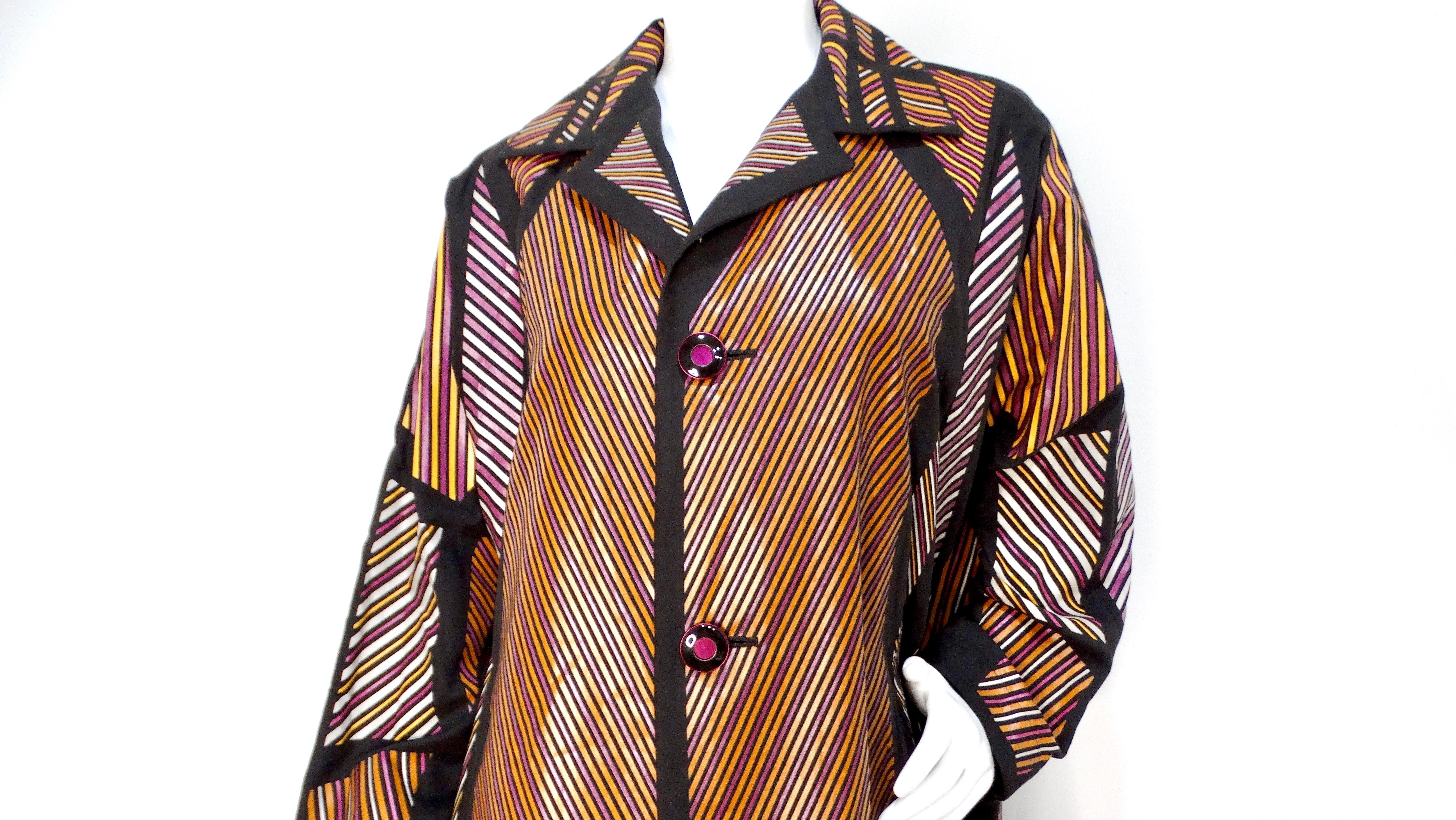 Il cappotto da auto a righe multicolore di Issey Miyake è un pezzo di grande effetto che combina colori audaci e design giocoso. Questo cappotto accattivante è caratterizzato da vivaci strisce viola, bianche e marrone-oro su un'elegante base nera,
