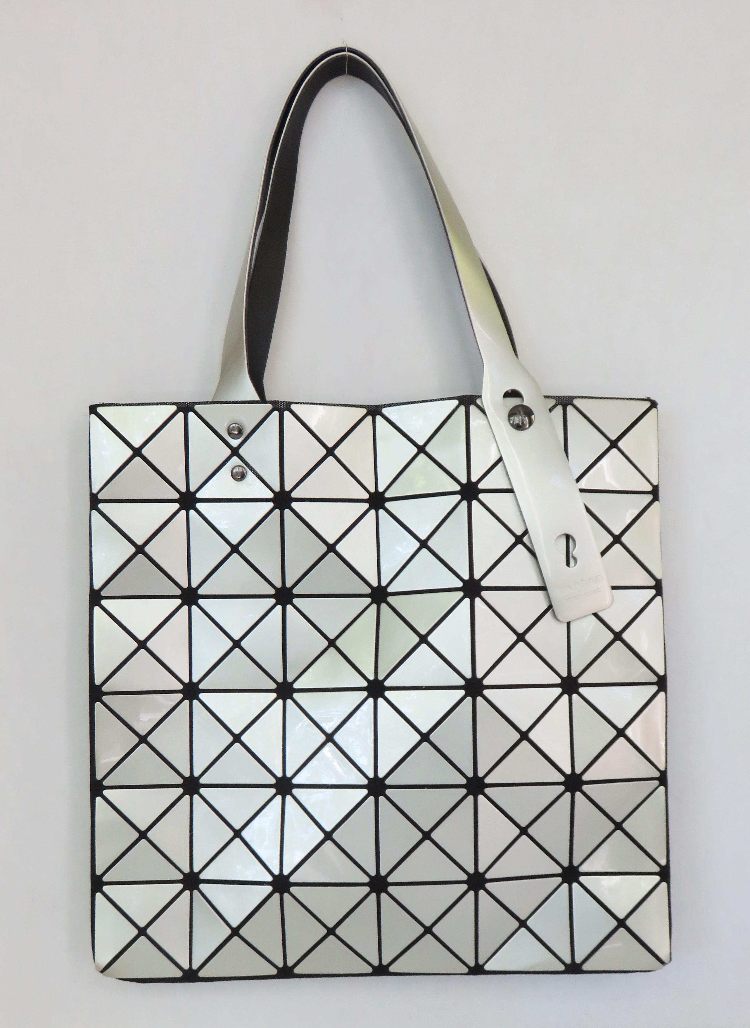 A new silver Bao Bao handbag by Issey Miyake. The bag consists of black mesh with geometric silver PVC overlay appliques, 2 top adjustable handles, an inner zipper pocket and and top zipper closure. Never used.

13.50 X 13.50