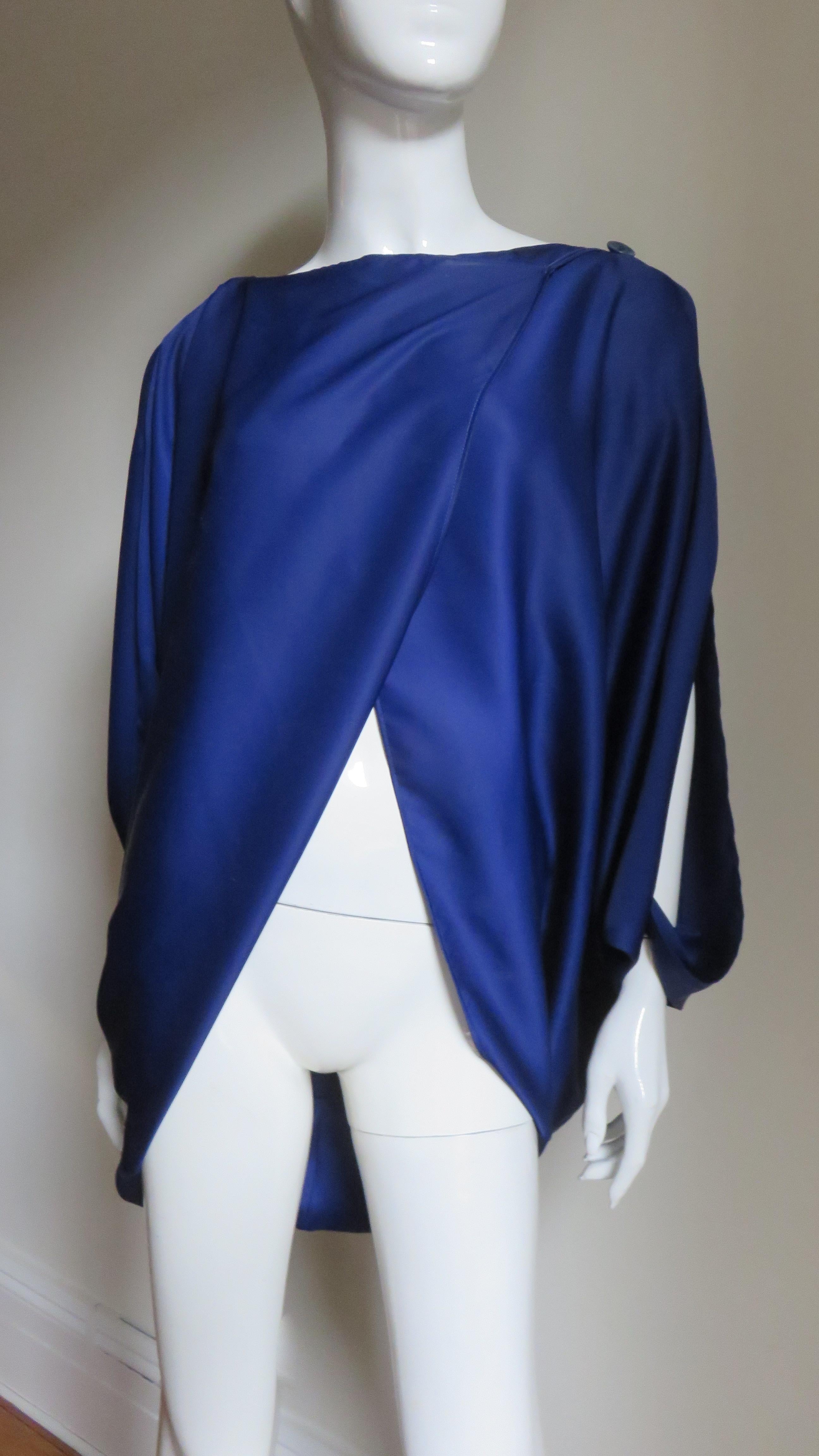 A fabulous blue top, shirt from Issey Miyake.  It overlapping at the front exposing the waist and buttons at the shoulder.  The back is fuller and longer and the sleeves are open from shoulder to wrist.
Fits sizes Small, Medium, Large.  One size