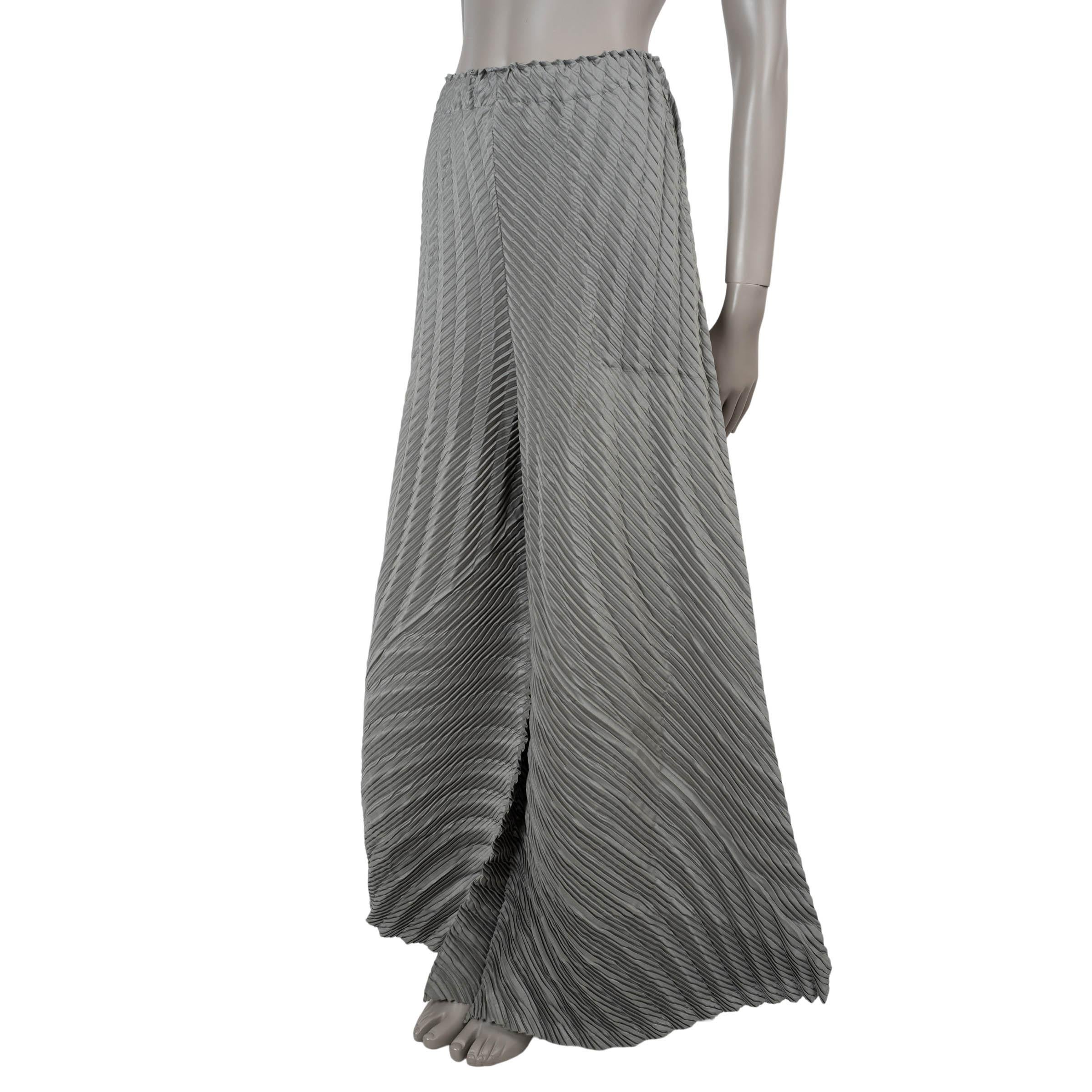 These 100% authentic Issey Miyake pants in fog grey plissé polyester (100%) showcase the brand’s iconic sculptural pleating with effortless sophistication. Featuring a high waist and asymmetrical wide legs, they are designed with practical side slit