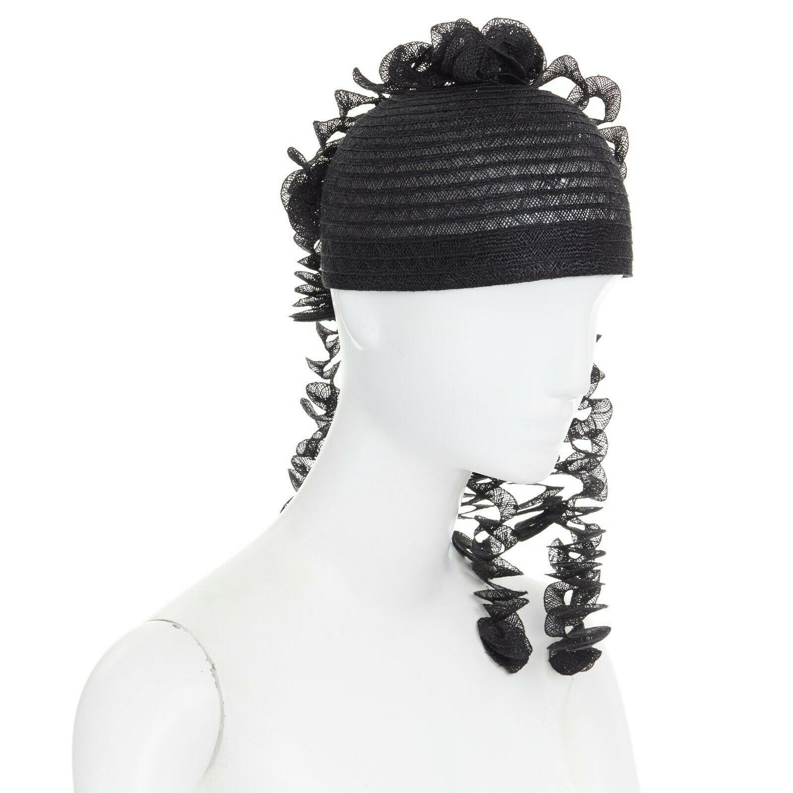 ISSEY MIYAKE PLEATS PLEASE
Black raffia straw knit. Round pullover cap. Draped spiral dangling strips. Statement party hat. Grosgrain trimmed along lining. Made in Japan.

CONDITION
New without tags.