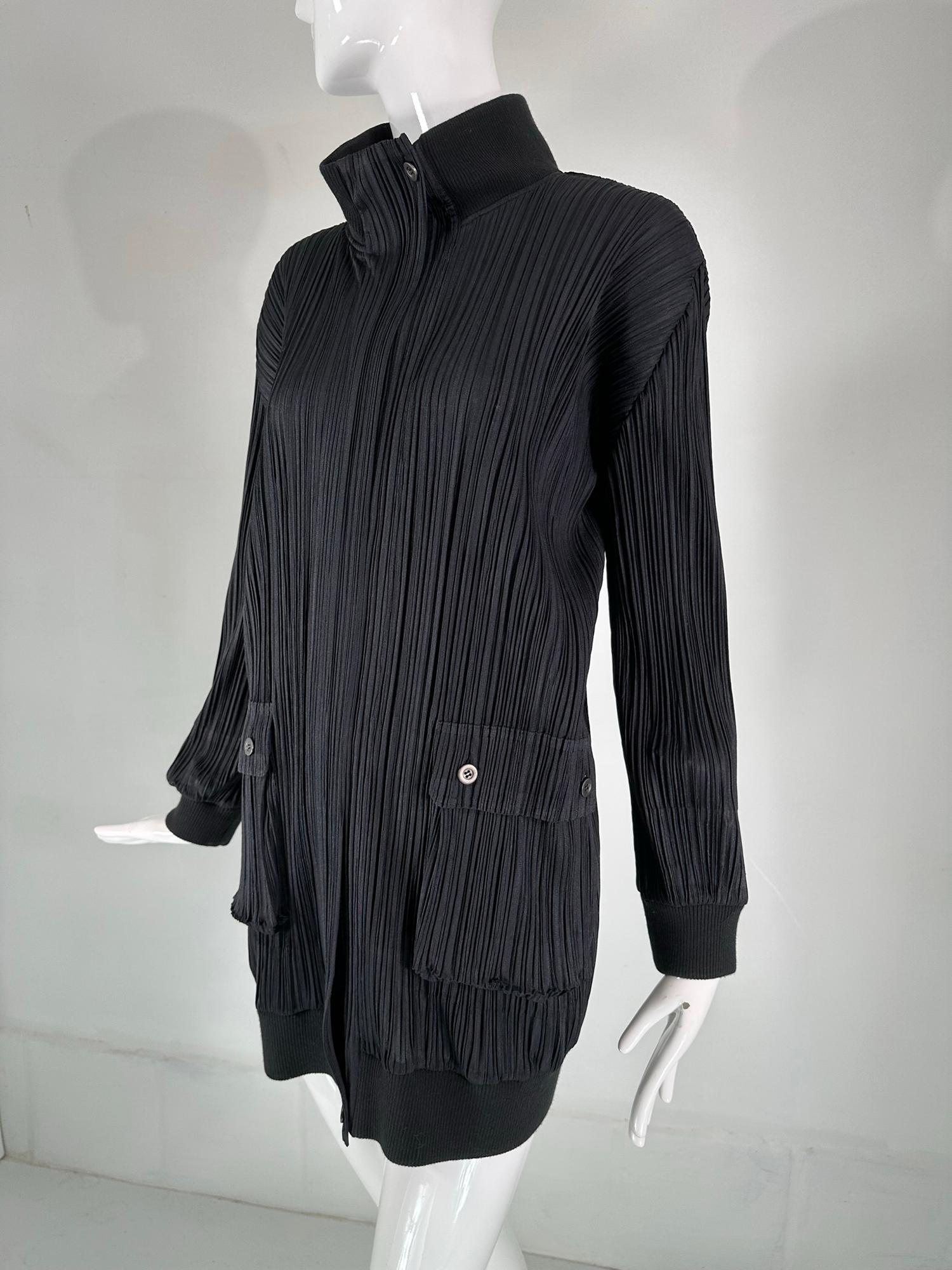 Issey Miyake Pleats Please black funnel neck, hidden zipper front long jacket. Long sleeve jacket has ribbed cuffs, closes at the front with a chunky zipper that is hidden with a side placket, it buttons at the top & bottom. There are hip front,