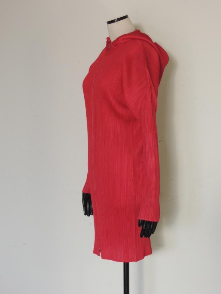Hooded coat, full front zipper, in magenta by Issey Miyake from the Pleats Please collection.

Mid calf length.

100% Polyester.

Tagged a size 5.

There is a significant amount of stretch in the fabric.

This is in excellent pre-owned condition