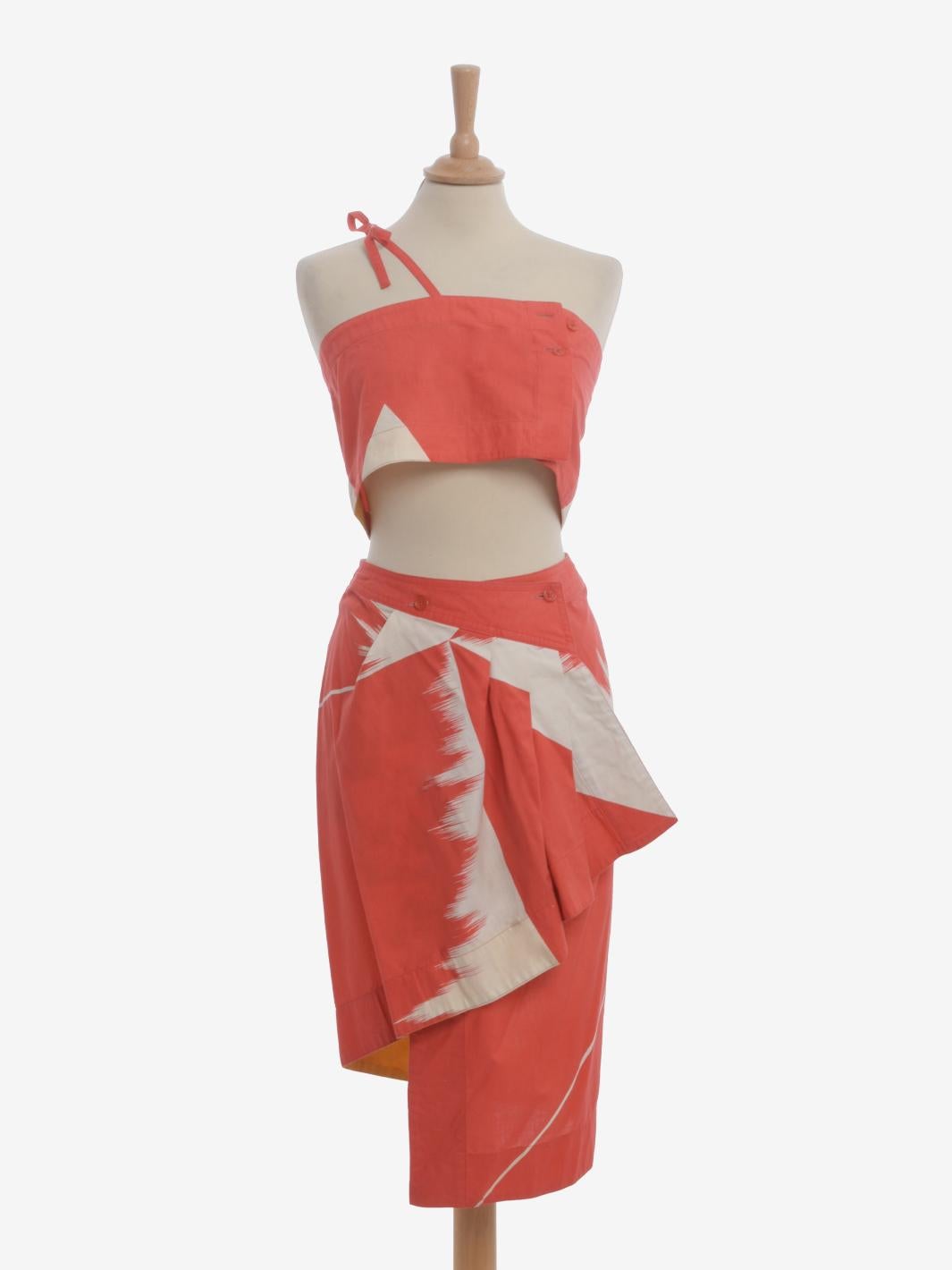 Issey Miyake Suit est un tailleur deux pièces appartenant probablement à la collection de printemps de la fin des années 1970. Le vêtement se compose d'un haut bandeau avec fermeture à deux boutons et bretelles simples croisées et d'une jupe crayon