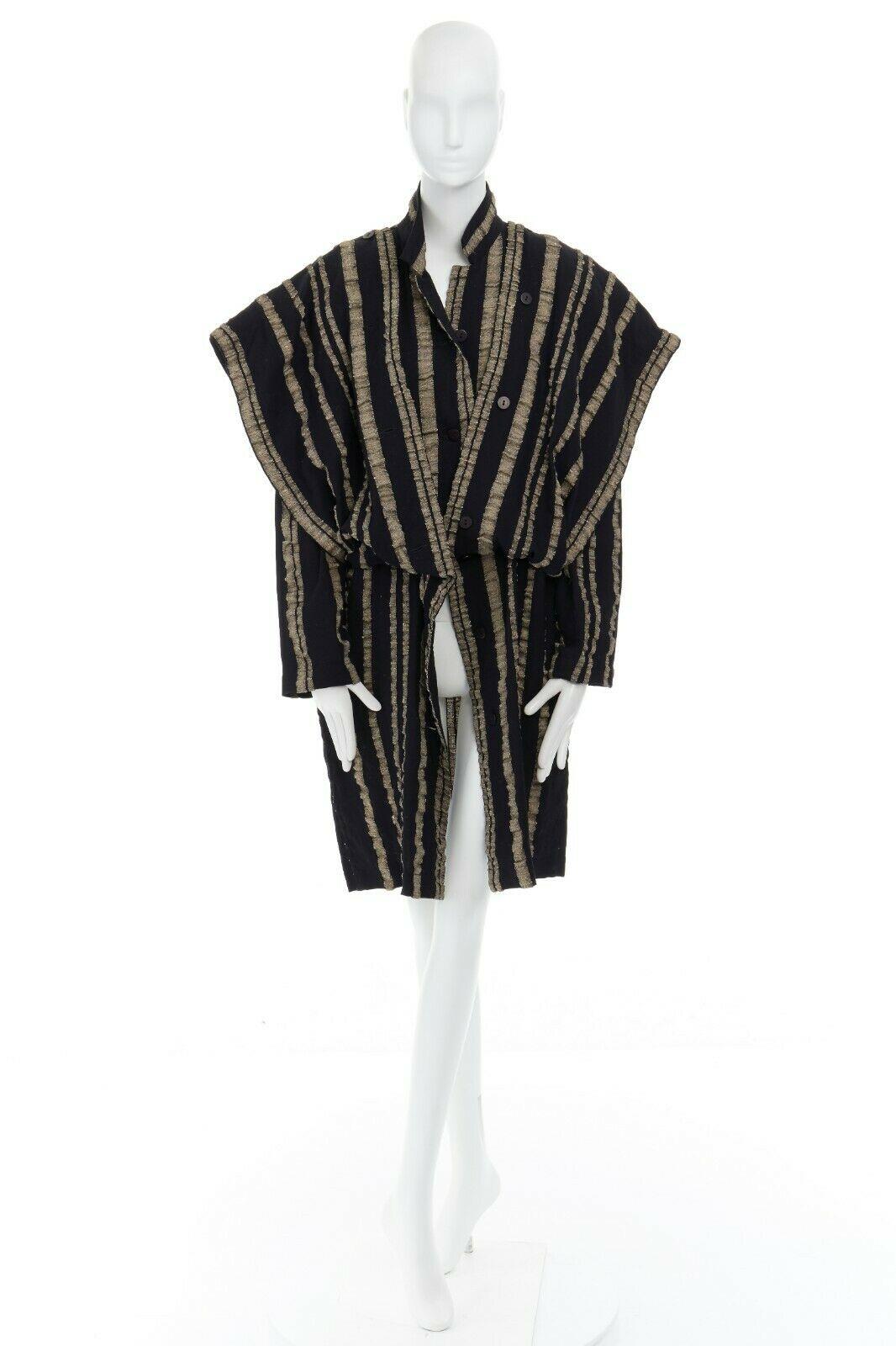 ISSEY MIYAKE 
CIRCA 1980'S VINTAGE LABEL
100% wool • Black beige vertical stripes • Notched collar • Attached panel from waist that could be worn draped or around shoulder for a sculptural samurai shoulder • Long sleeve • Button front closure •