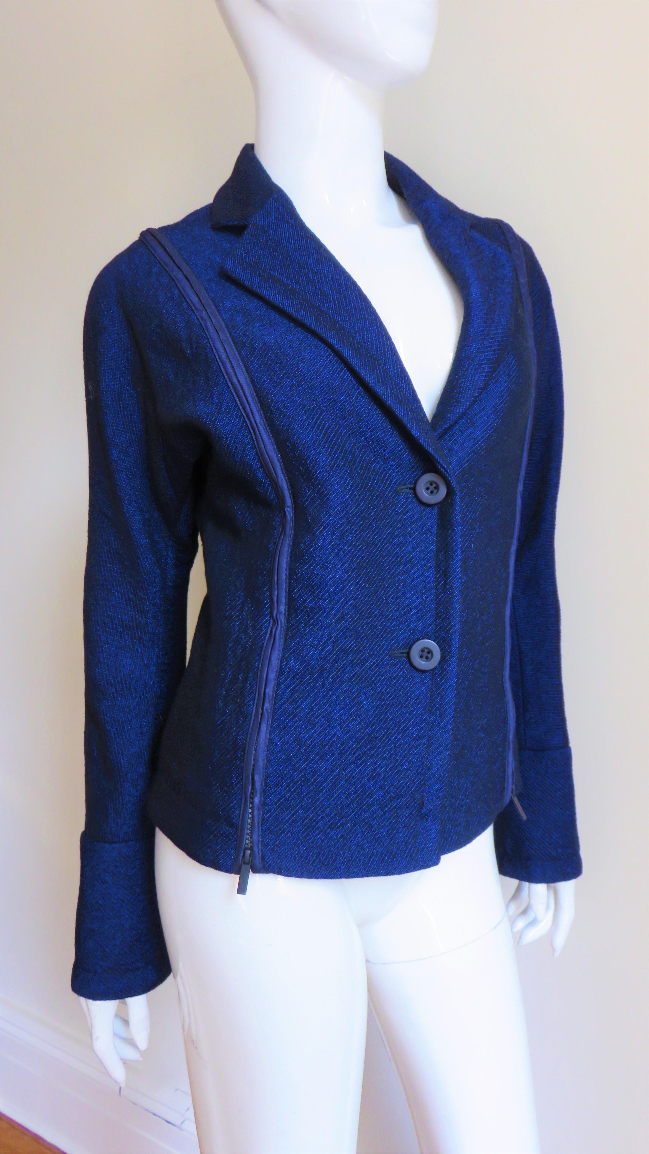 A fabulous bright blue wool jacket by Issey Miyake. It has a lapel collar, black button front closure, long dolman sleeves with zipper cuffs and fabulous vertical zippers along each side of the front and back which open to reveal matching nylon