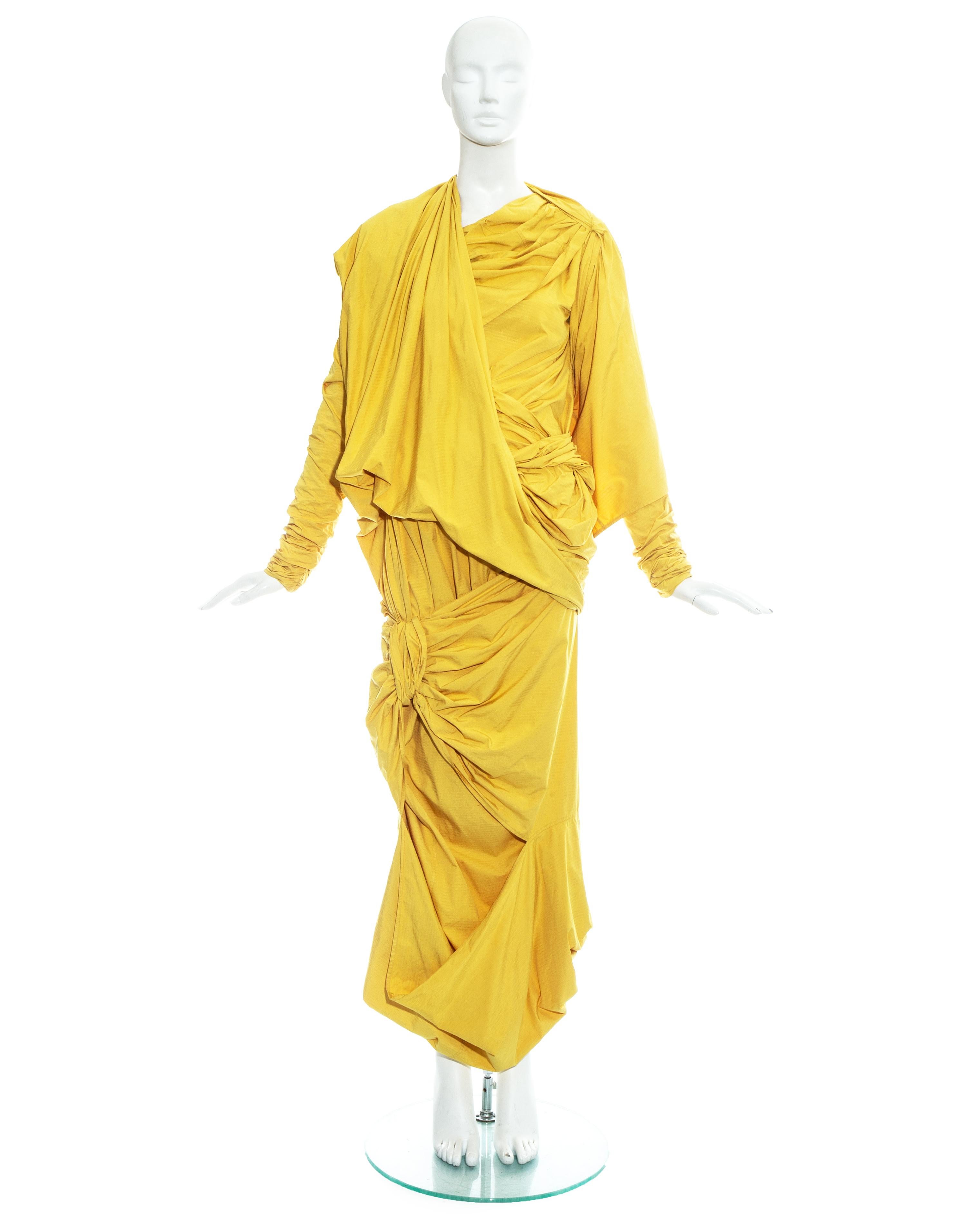 Issey Miyake, yellow parachute ensemble made from a high-density, crease-free woven fabric; thin and lightweight, with a texture like a piece of paper. Blouse with ruched double layered sleeves, pleated bust with asymmetric drape and optional hood.